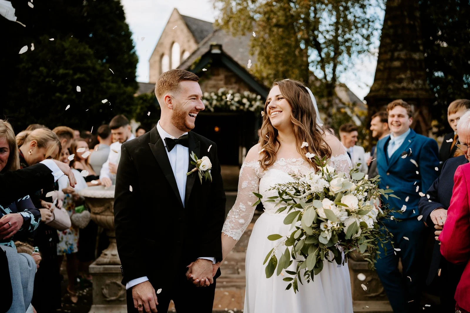 Amy and James walking through church confetti, a photograph from their wedding used as the highlight cover