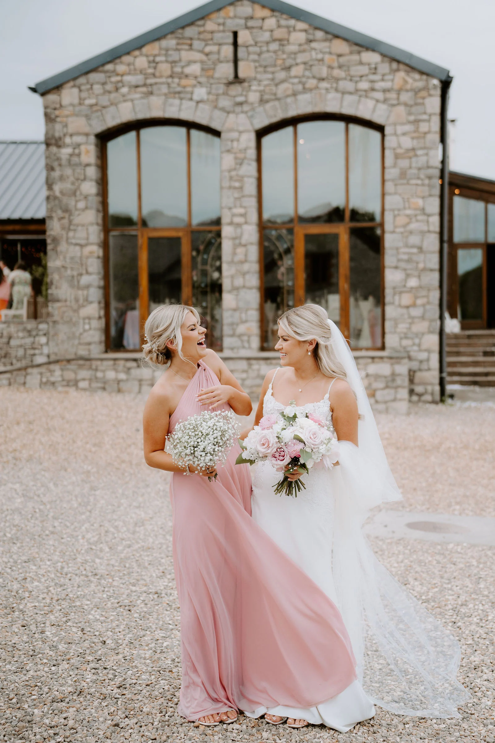 Bride and groom laughing together in the rustic courtyard at Rosedew Farm
