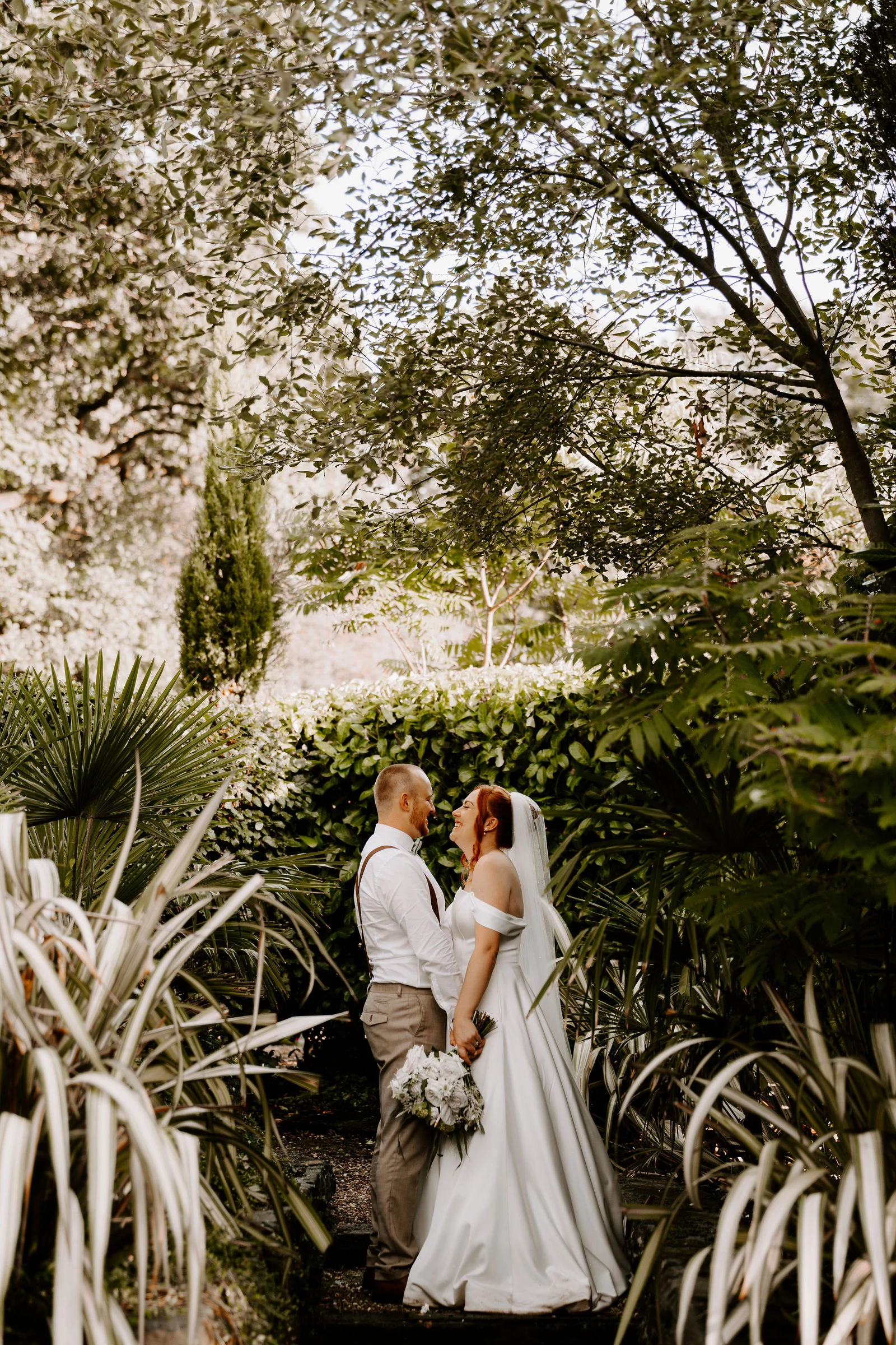 Intimate portrait of newlyweds resting by the garden trees