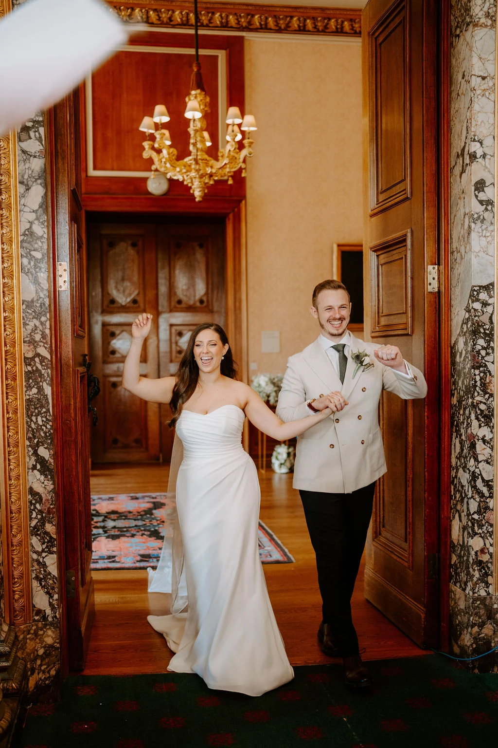 Phil and Natasha holding hands in a richly coloured room at Ashridge House