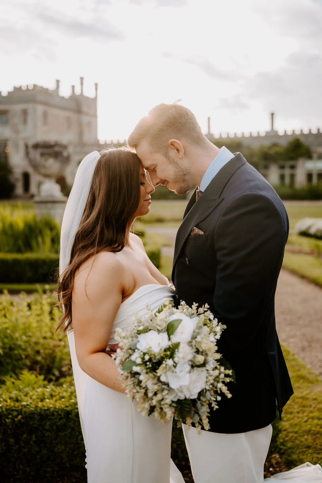 Phil and Natasha touching foreheads with Ashridge House behind them
