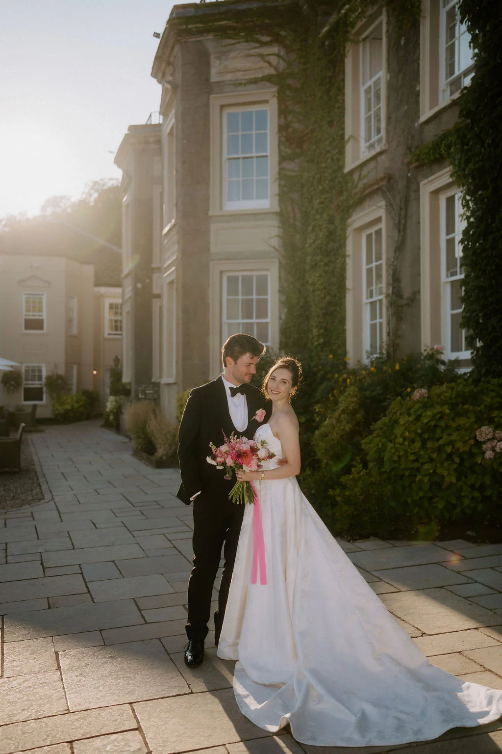 Louisa & Chris | City Lights at Dusk Intimate newlywed embrace on the terrace as the evening city lights begin to glow across Cardiff