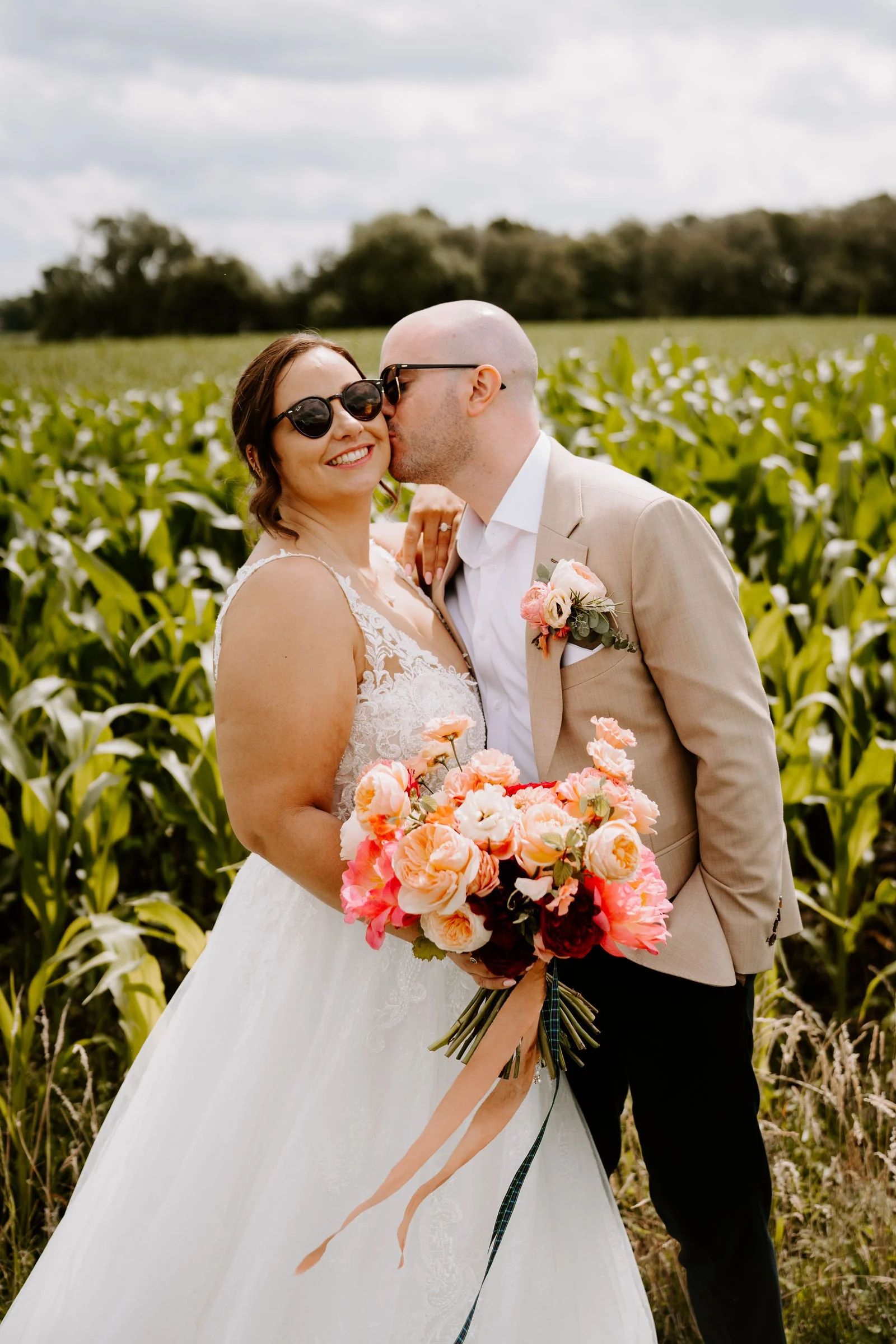 Lauren and Jon kissing among tall maize plants at Alcumlow Wedding Barn