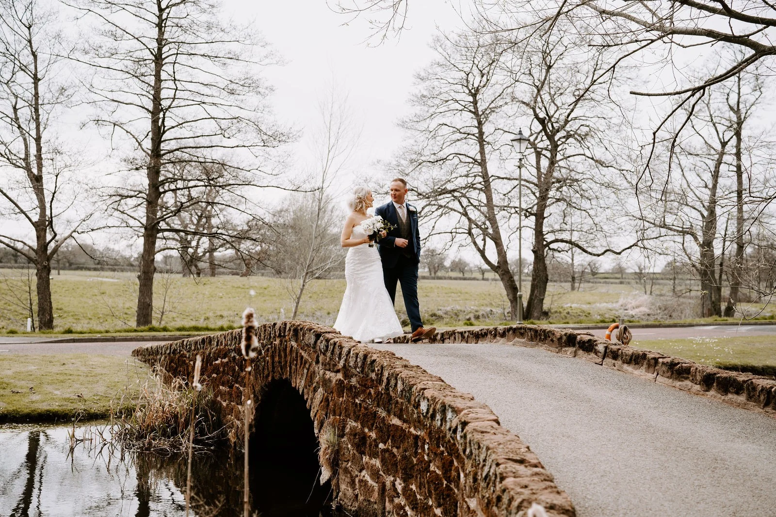 Emma and James kissing on a small brick bridge in the grounds at Carden Park Hotel