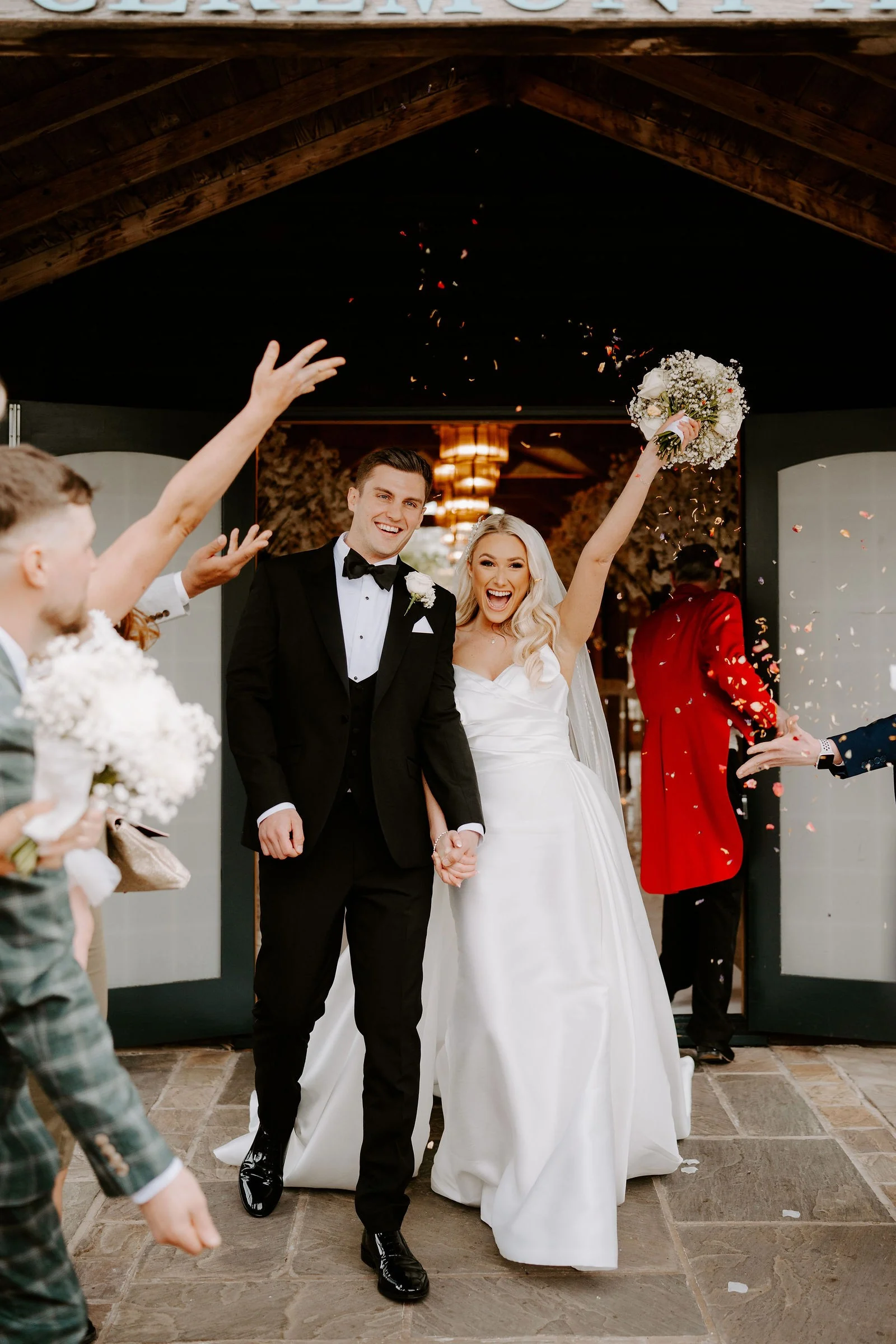 Hannah and Rob walking through confetti with their guests at Colshaw Hall