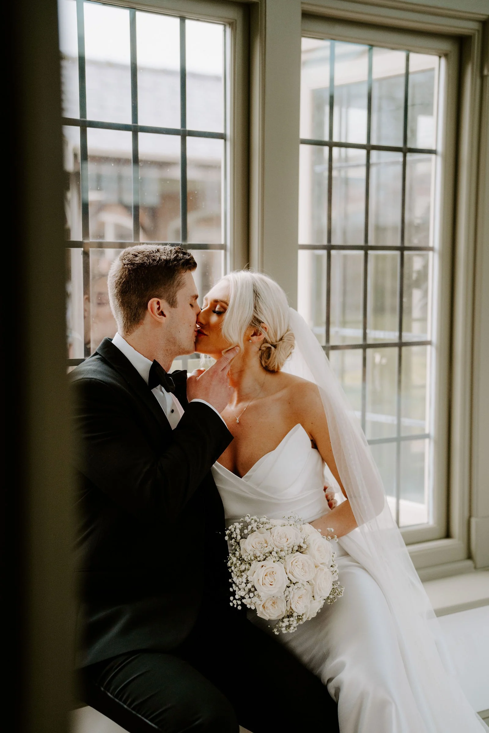 Hannah and Rob embracing with her bouquet and veil at Colshaw Hall