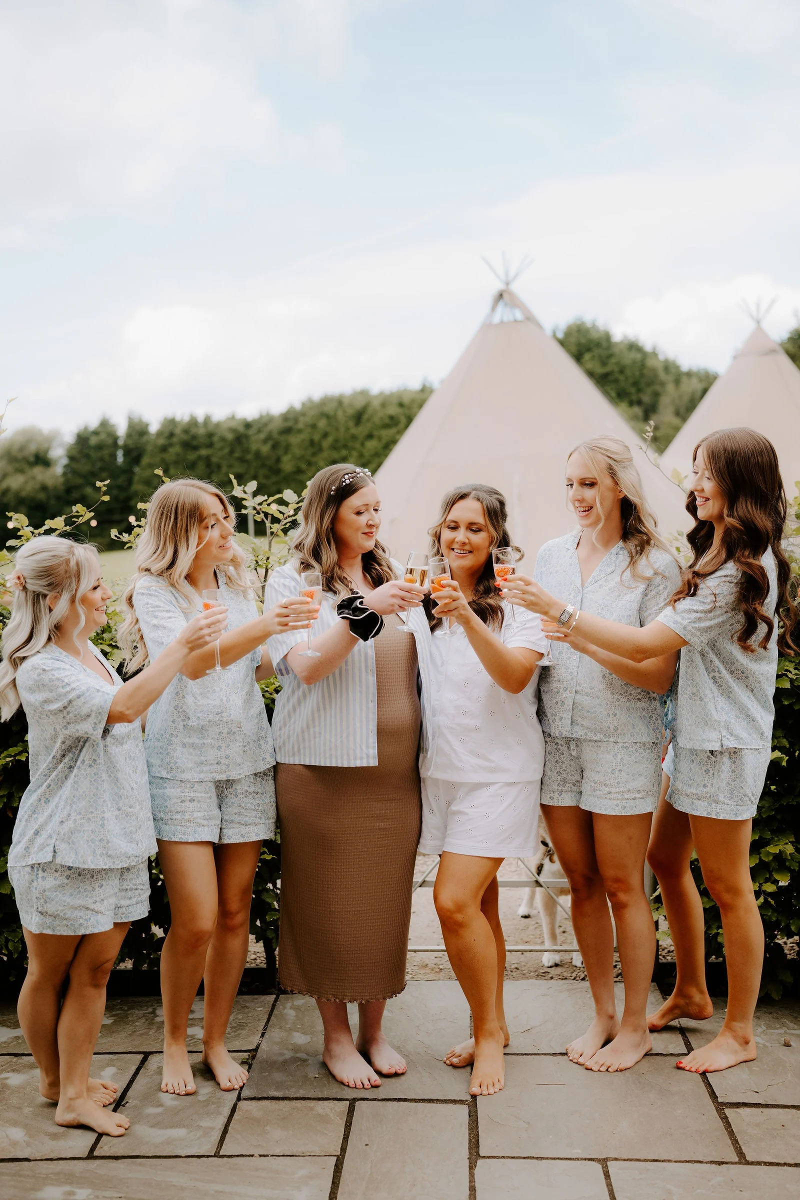 Rebecca and her bridesmaids raising their glasses outside the marquee at Duddon Mill Farm