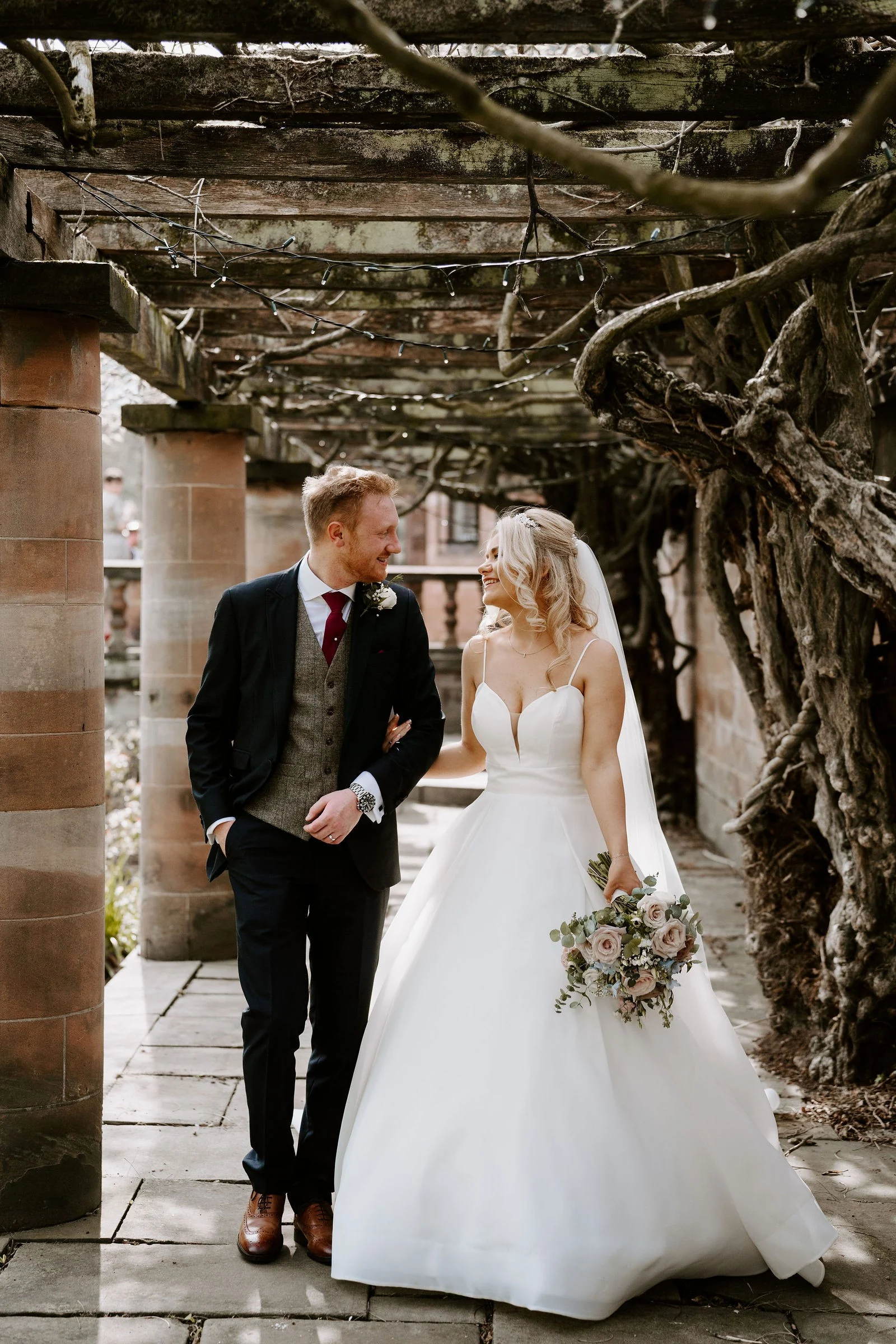 Gabi and Mikey walking beneath the brick columns and pergola at Inglewood Manor