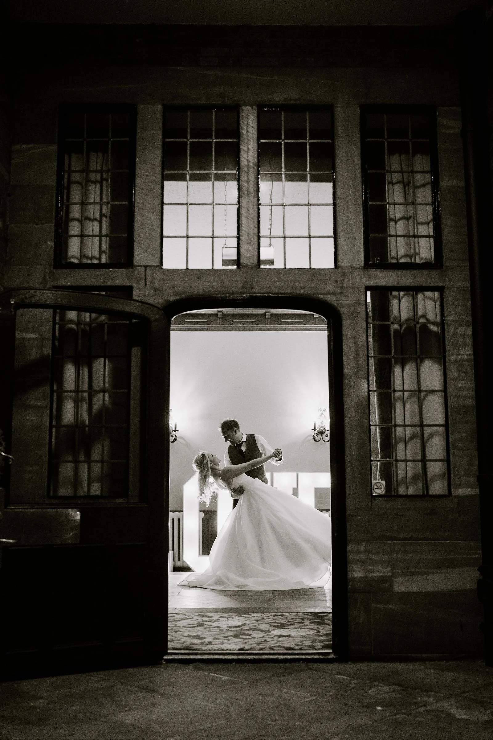 Gabi and Mikey dancing outside, seen through the glass doorway at Inglewood Manor