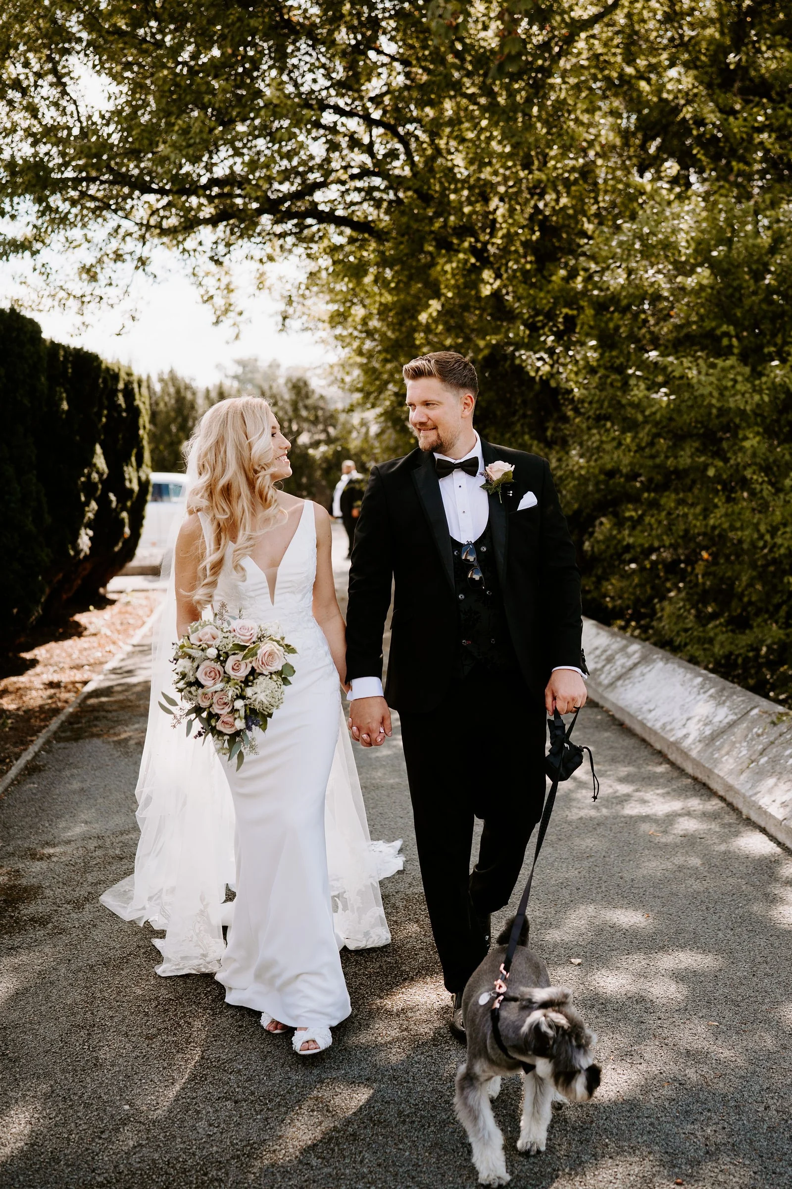 Chloe and John walking along a tree lined path with their dog