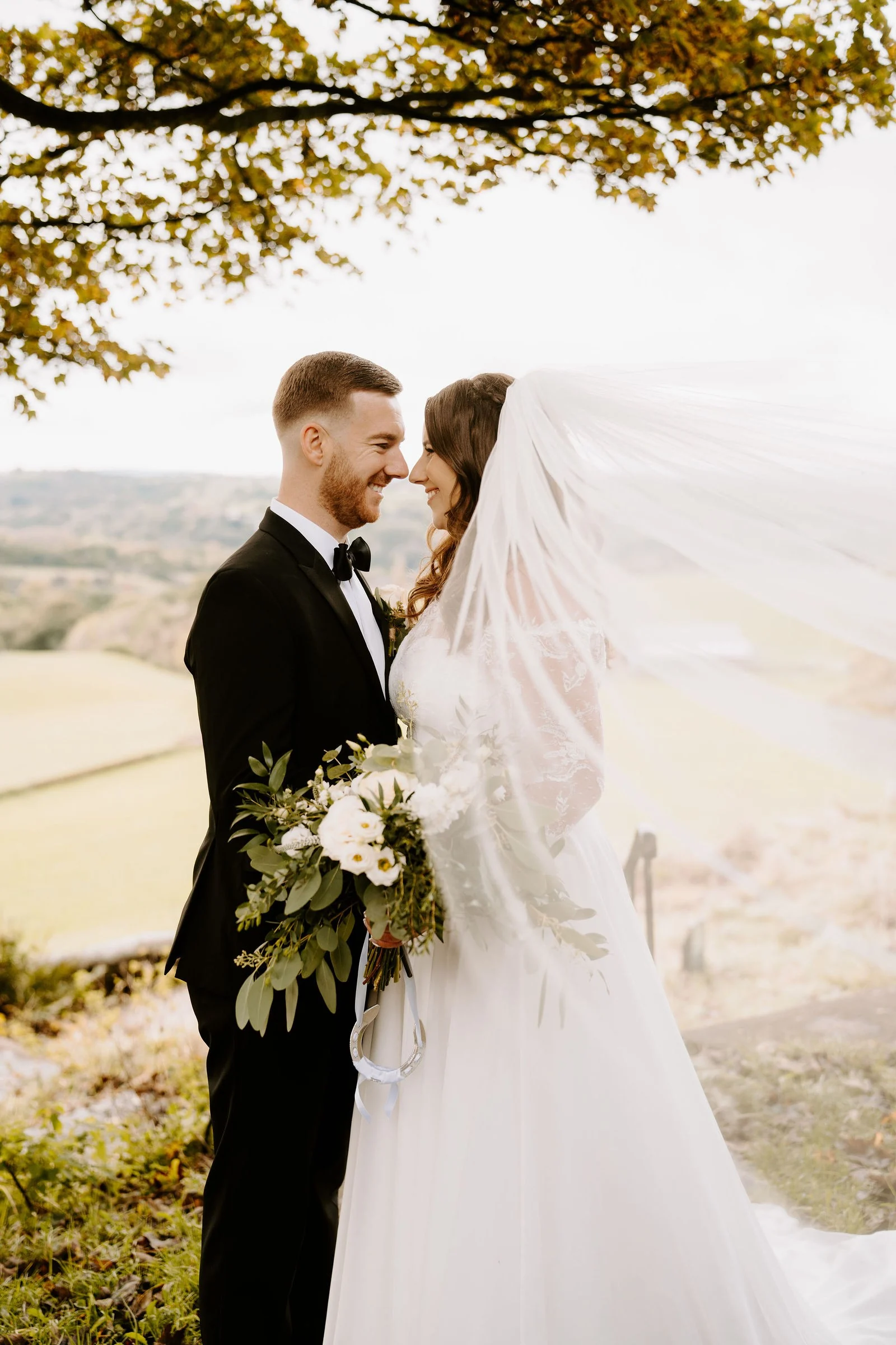 Amy and James kissing beneath a tree with autumn leaves at Shrigley Hall Hotel & Spa