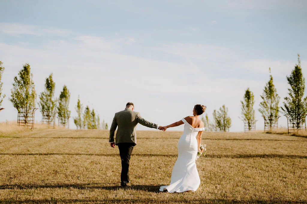 Laura and Jack walking hand in hand through the grounds at Cripps Barn