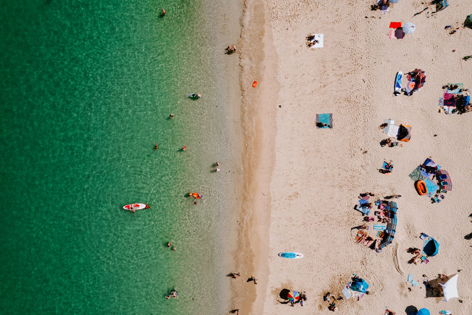 Drone aerial perspective of turquoise waves lapping against the golden sandy beach at Carbis Bay