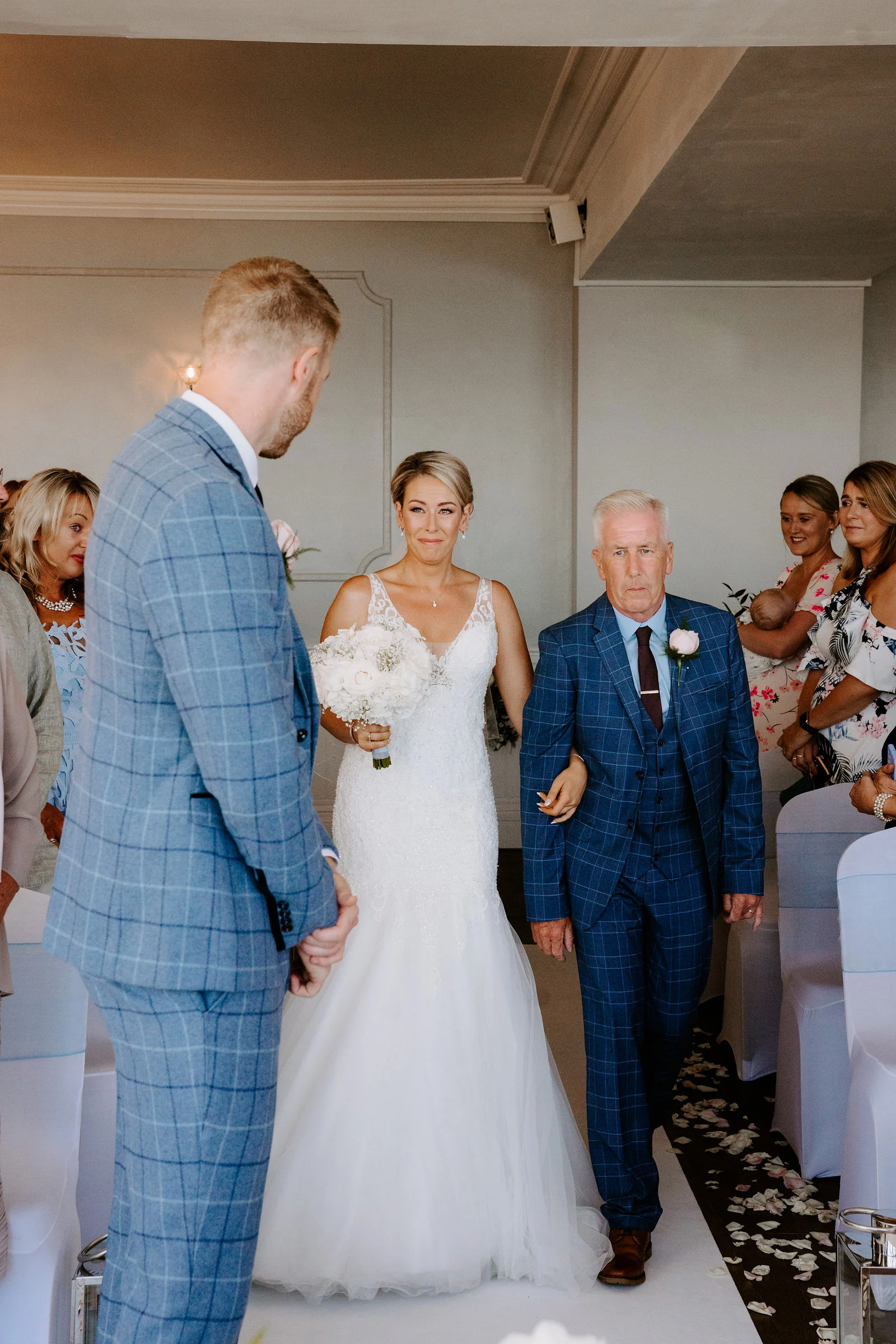 Sarah walking down the coastal ceremony aisle accompanied by her father