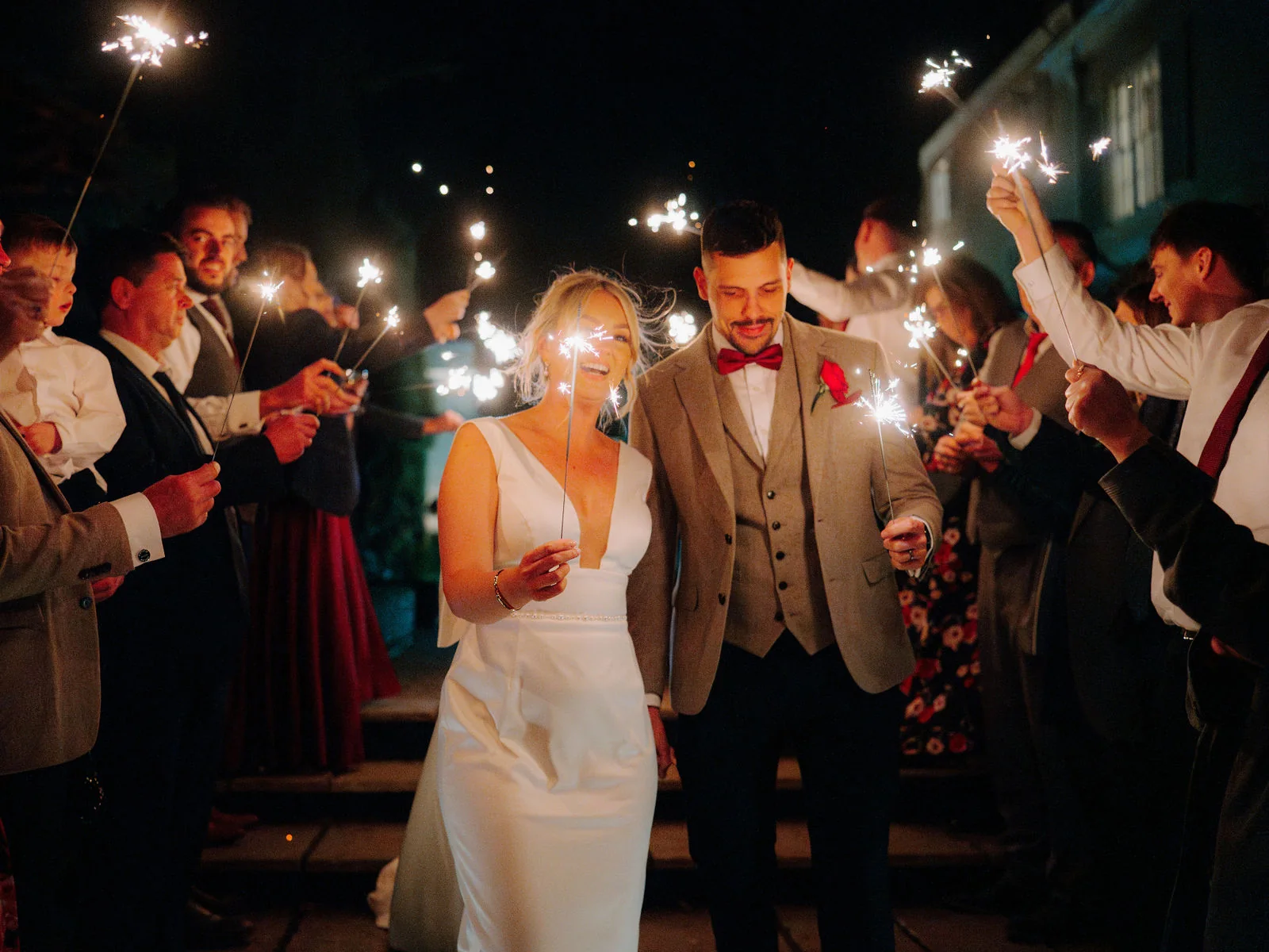 Chelsea and Liam walking through a sparkler arch at night at Deer Park Country House