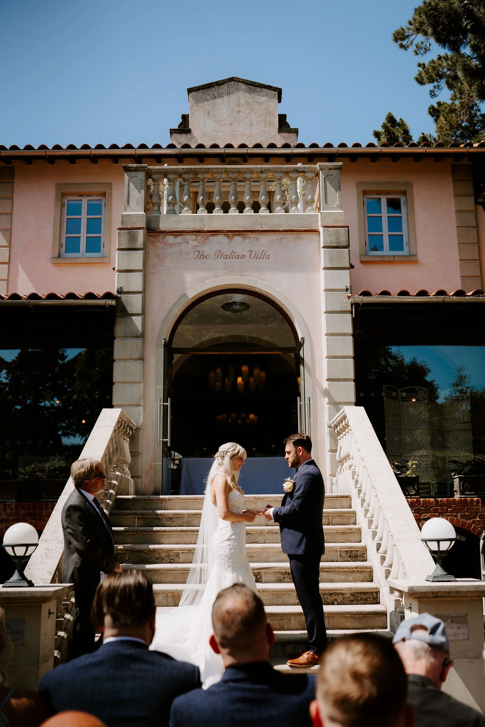 Erica and Pete exchanging rings during their ceremony on the villa steps