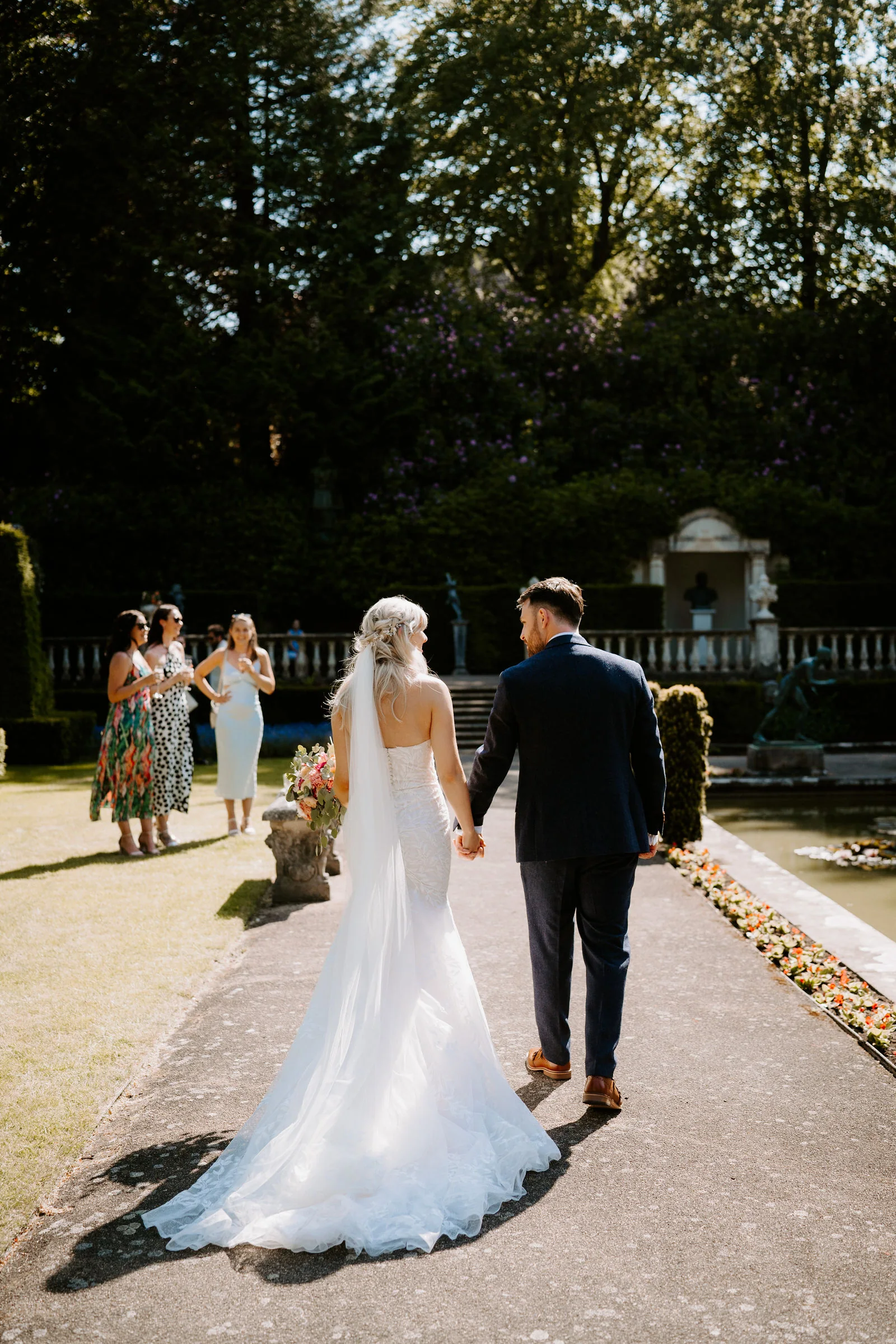 Erica and Pete walking hand in hand along the lily pond terrace at The Italian Villa