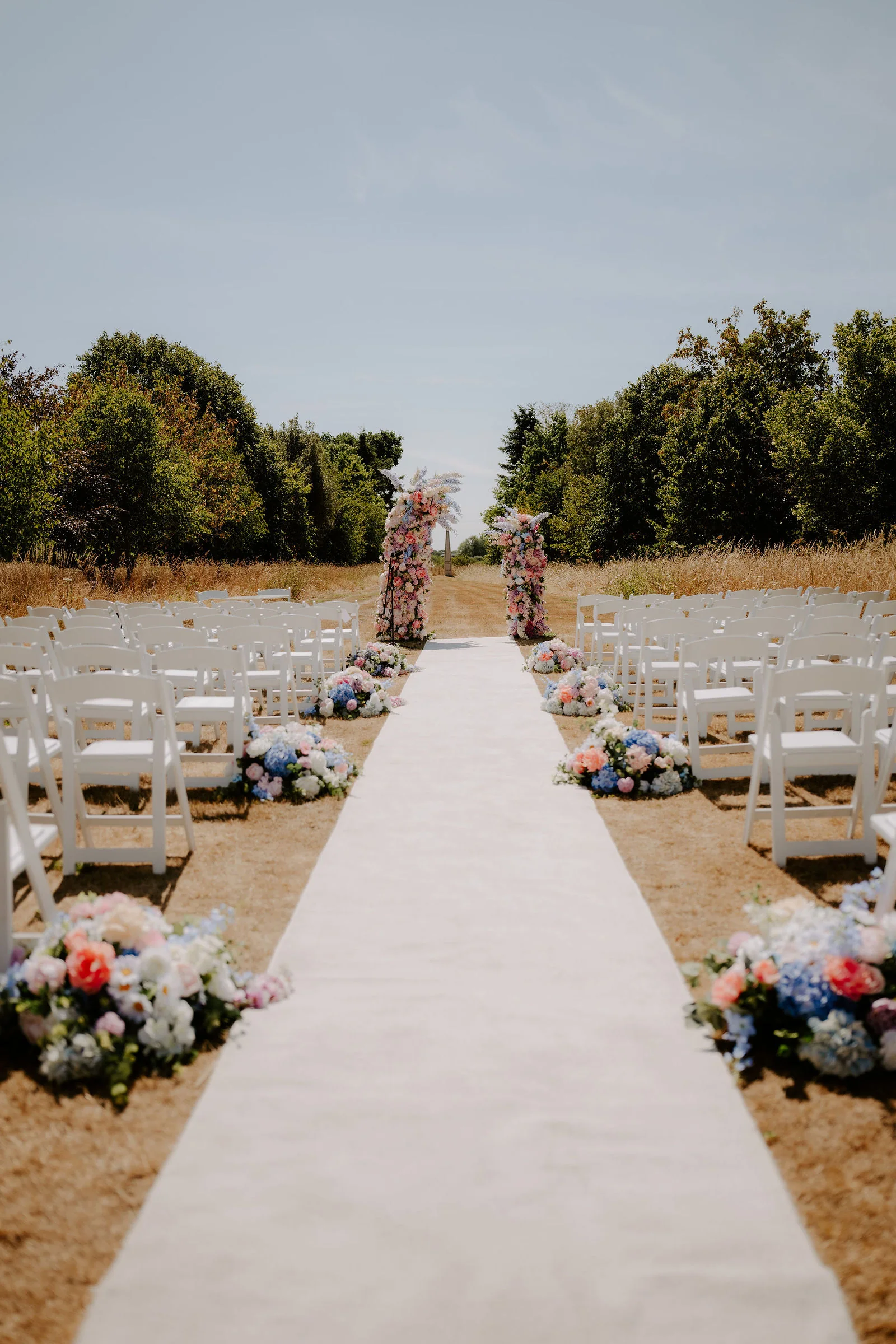 An outdoor ceremony aisle at Parley Manor with white chairs and flowers before guests arrive