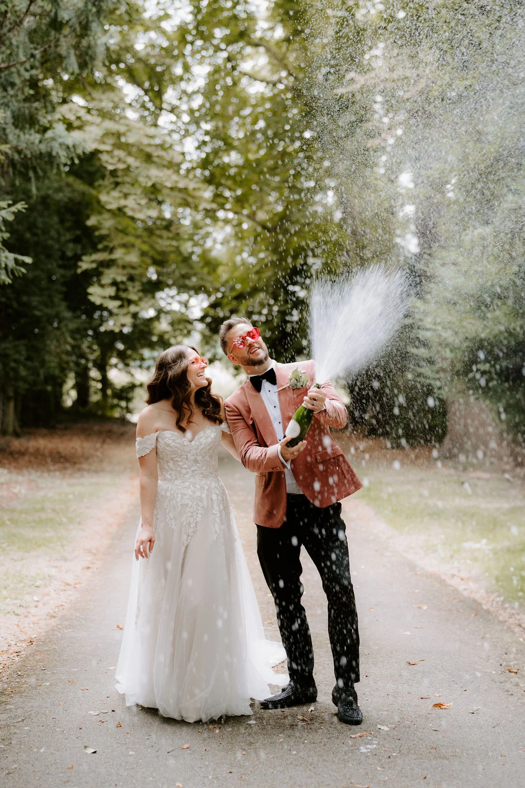 James and Laressa kissing beneath the trees with coloured smoke nearby