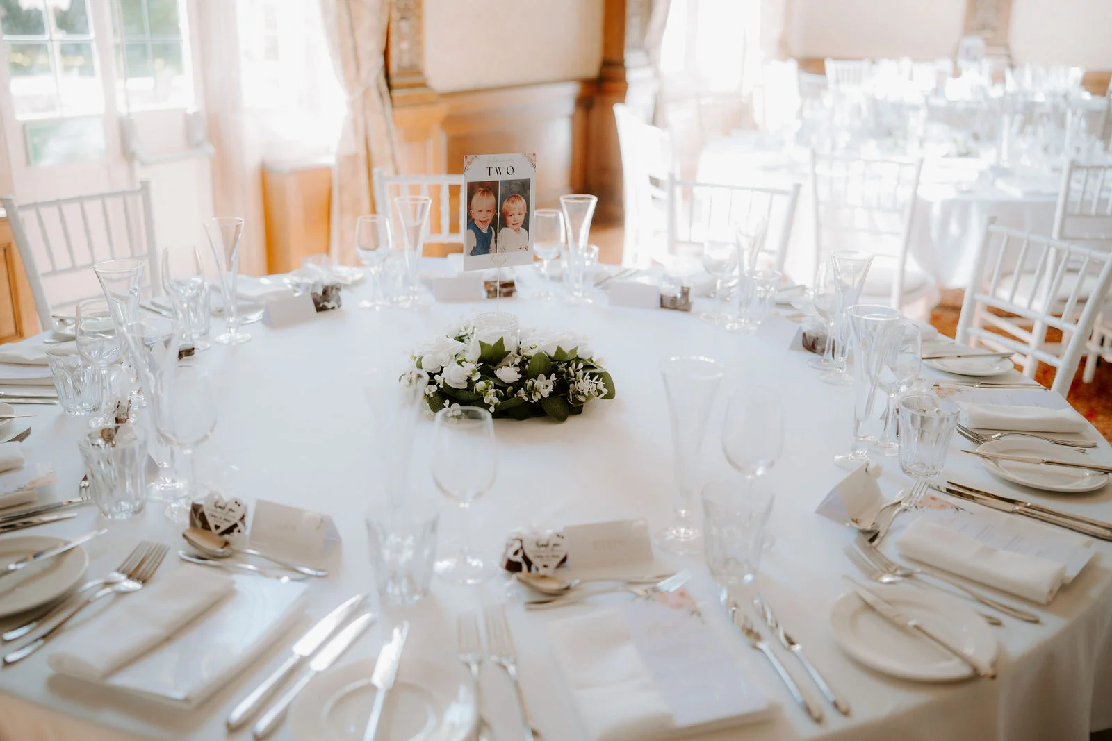Soft floral centrepieces and pale chairs at Chloe and Matt’s Beaulieu wedding reception