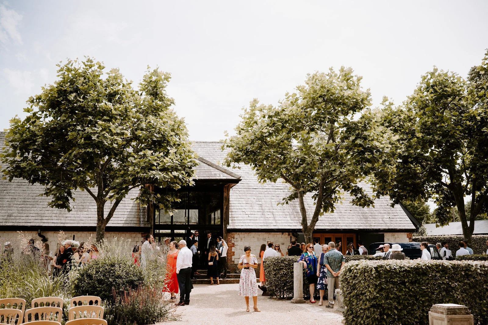 Bury Court barn and garden with guests arriving for an outdoor wedding ceremony