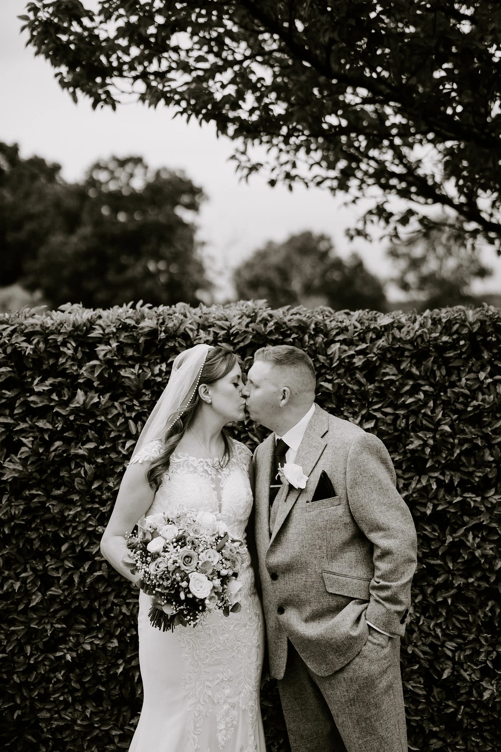 Black and white portrait of Stuart and Laura beside a garden hedge at Old Thorns