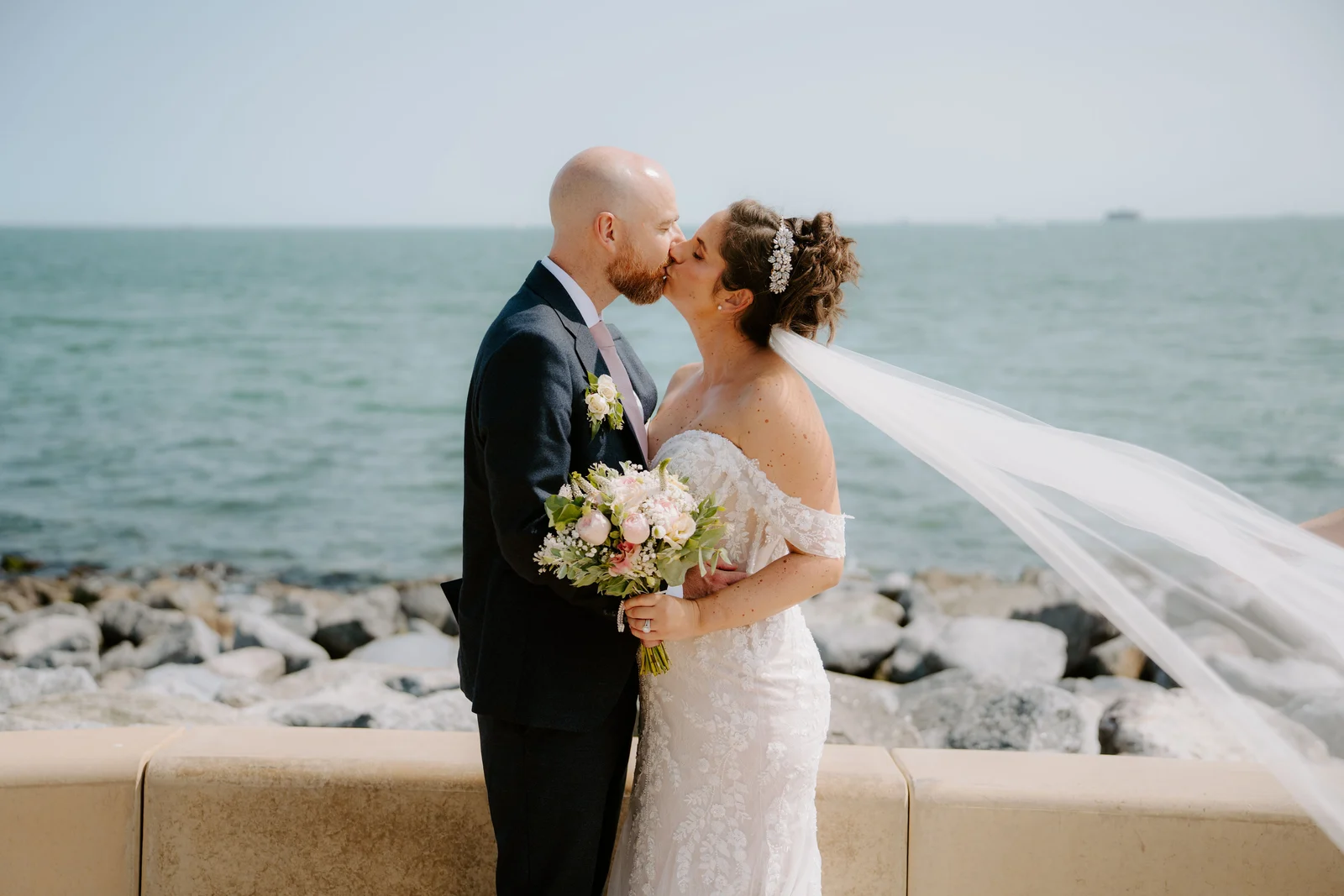Claire and James kissing beside the sea after their Square Tower wedding in Portsmouth