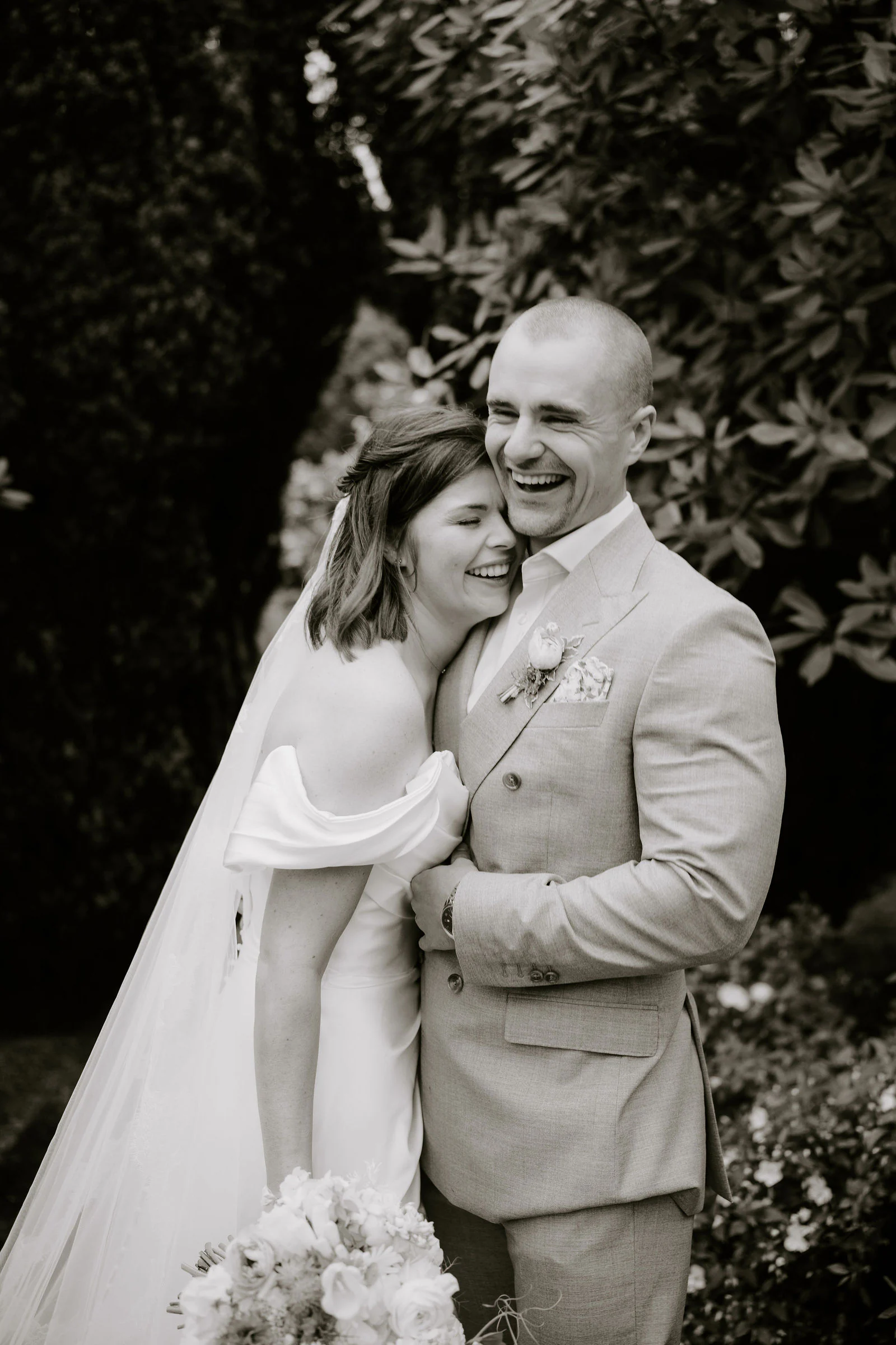 A bride and groom laugh together in a close black and white portrait at Hayne House near Hythe