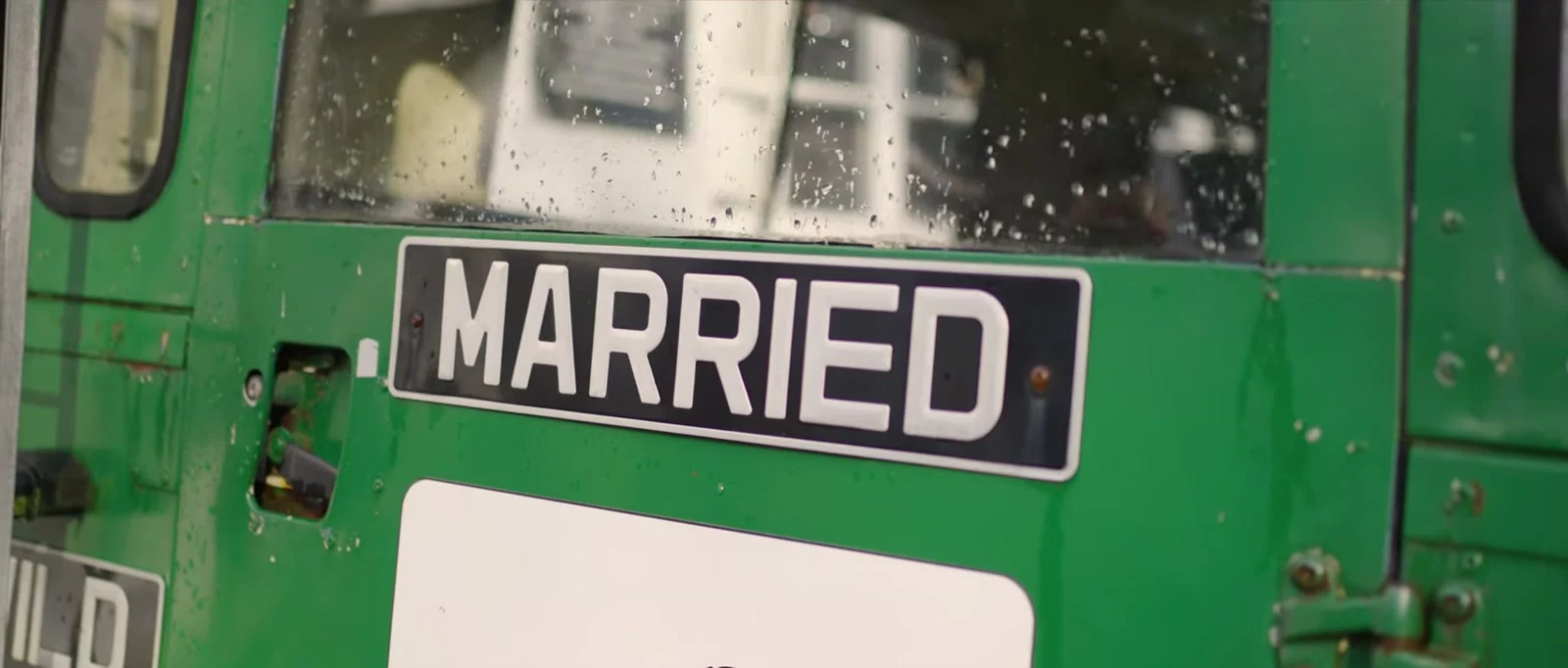 A MARRIED number plate on the back of a green Land Rover, with raindrops on the window above it