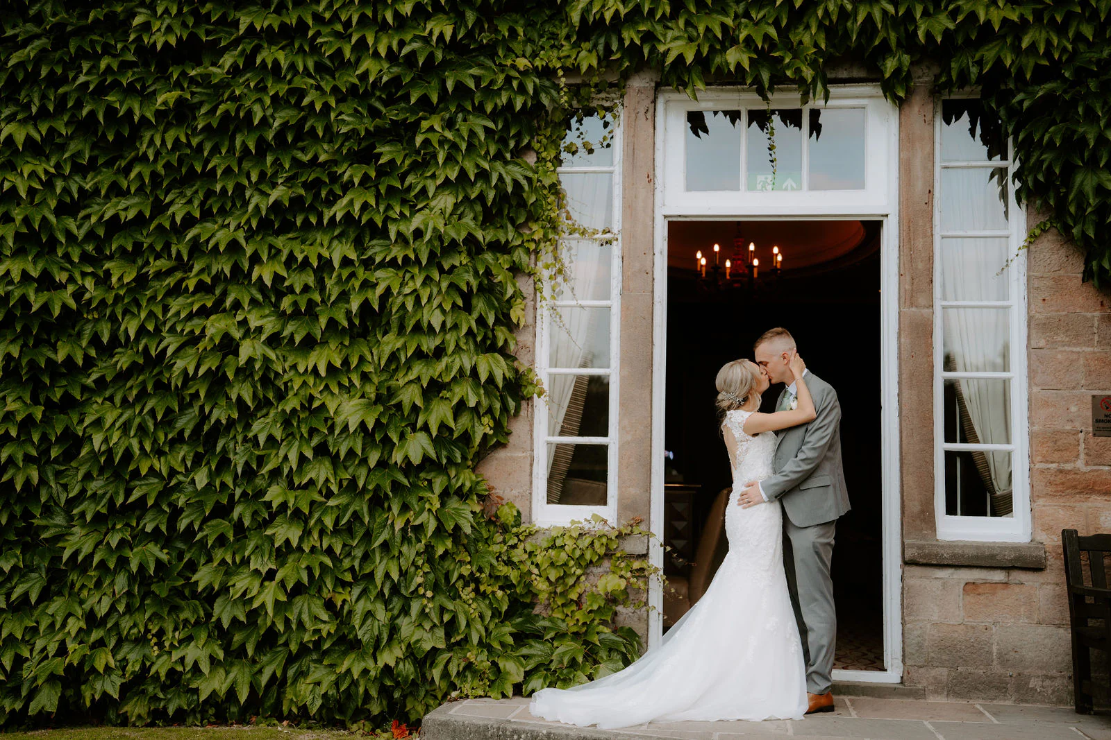 Brittany and Callum kissing in an ivy covered doorway