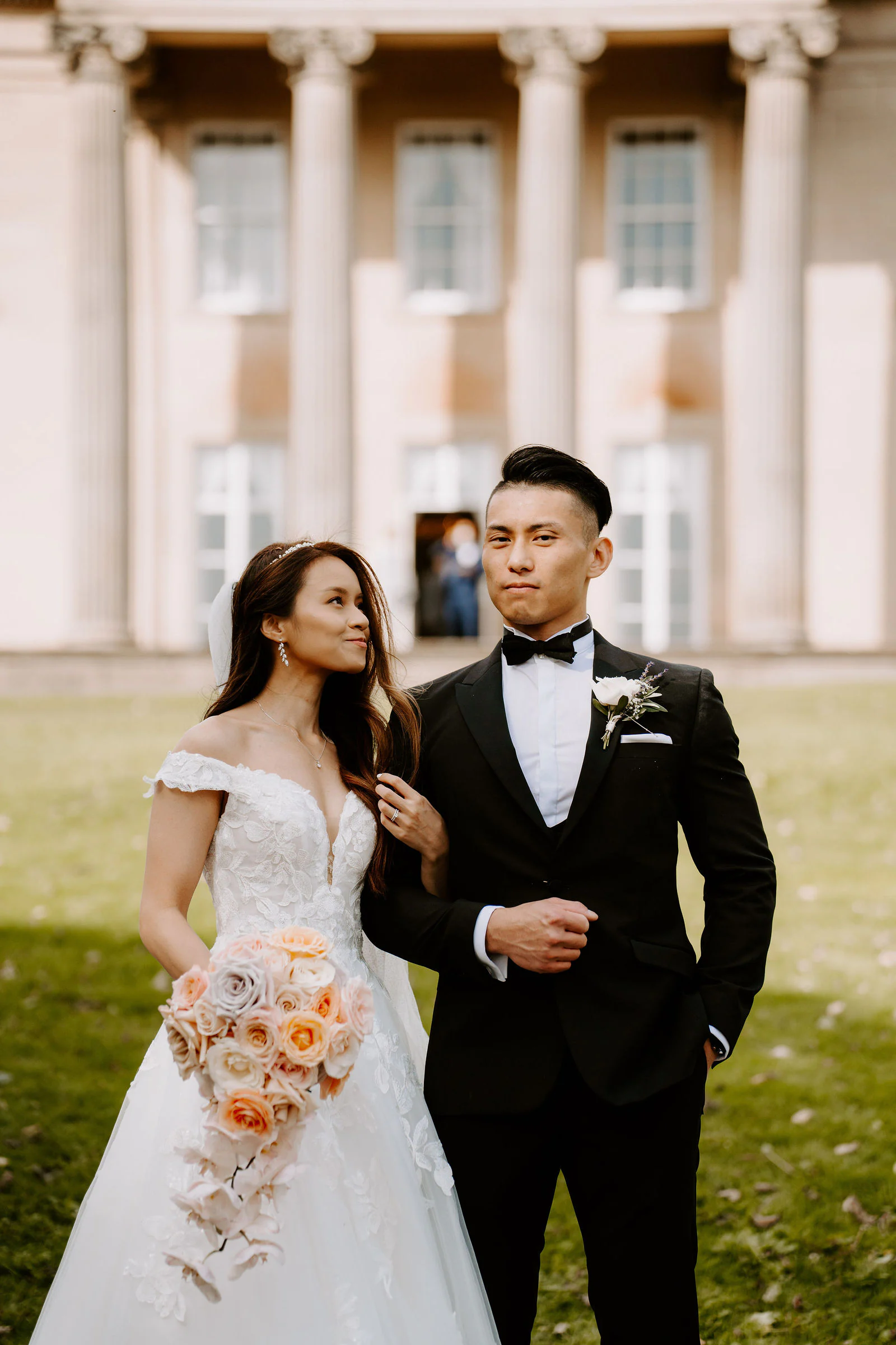 Sally and Lewis standing together in front of the tall columns of The Mansion in Roundhay Park