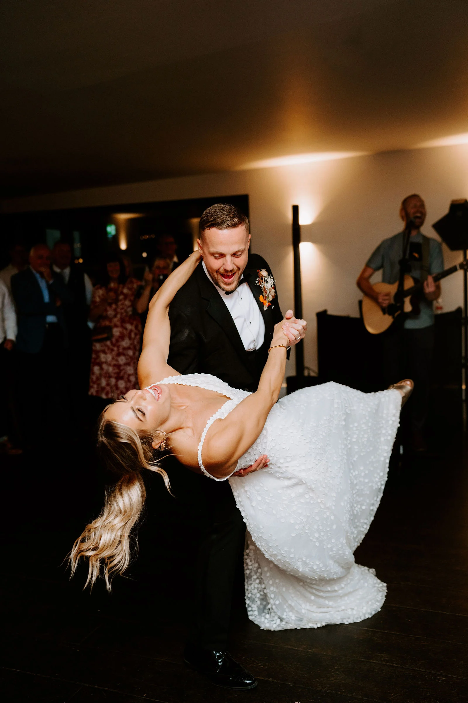 Tom dipping Emma while guests dance in the background