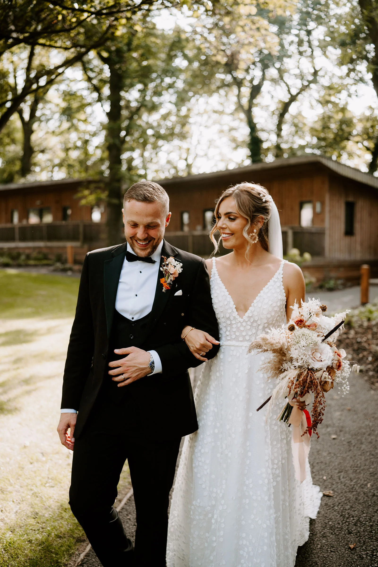 Emma and Tom walking together past the woodland lodges at Hothorpe