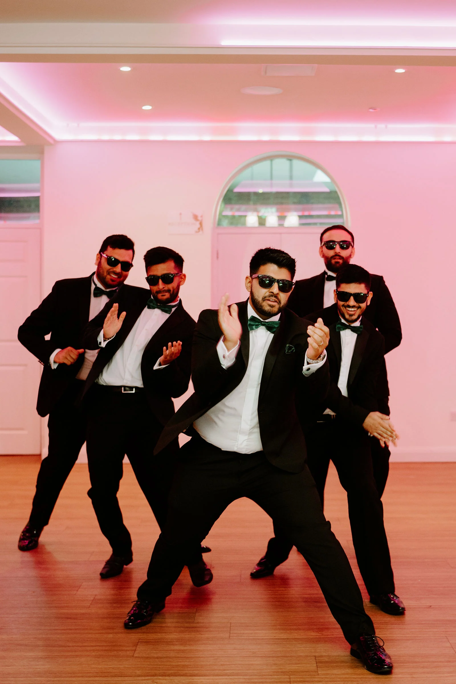 Sanjay and his friends posing playfully in a pink-lit reception room