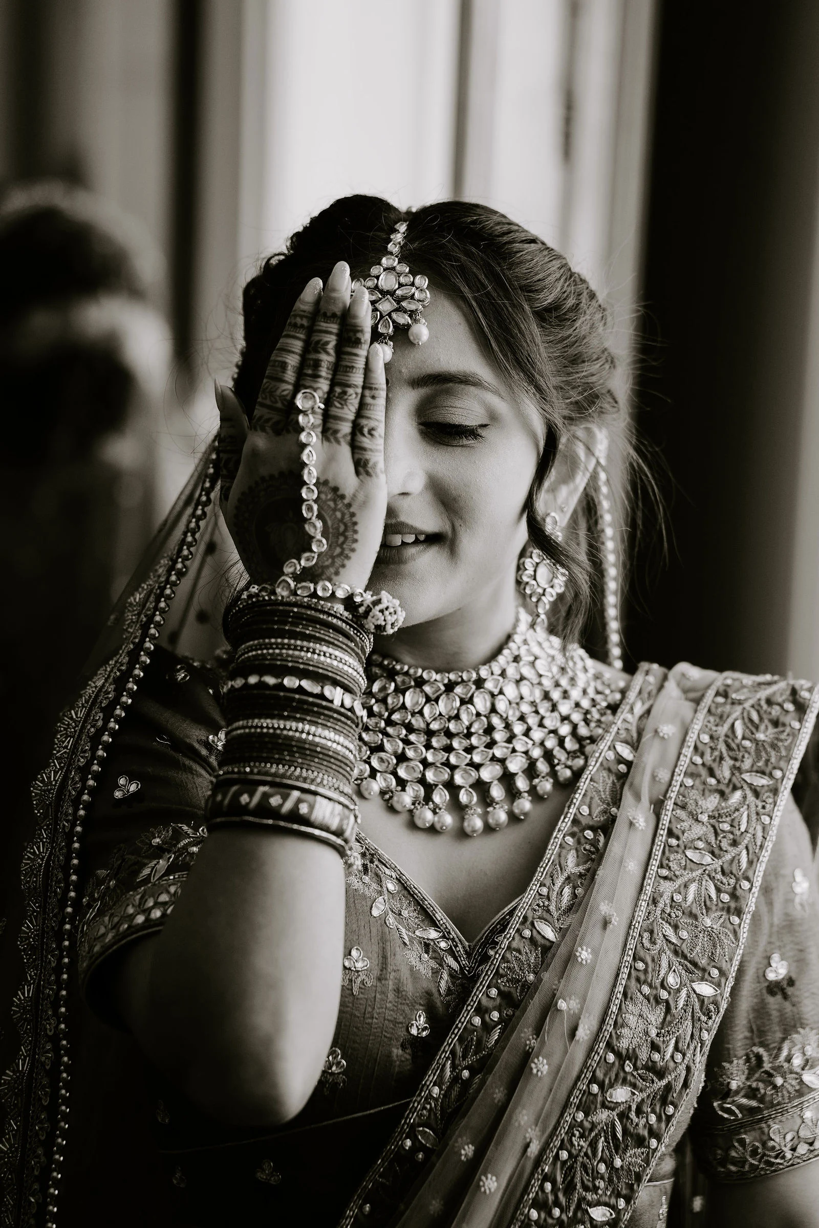 Nalini resting her henna-decorated hand beside her face, in black and white