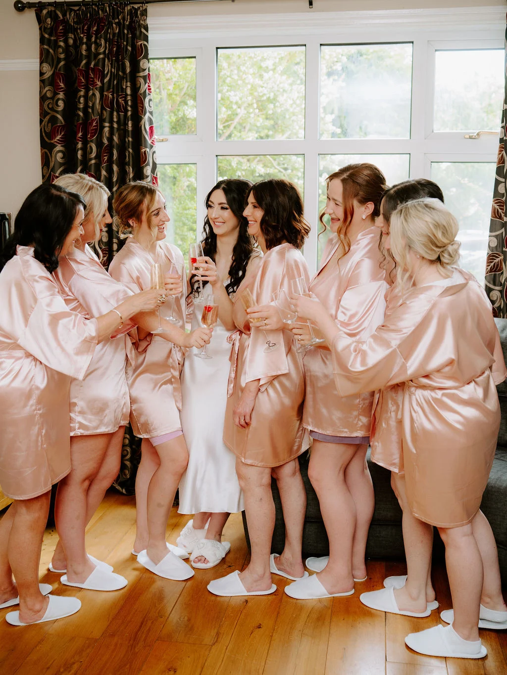 Carla with her bridesmaids beside a window during preparations.