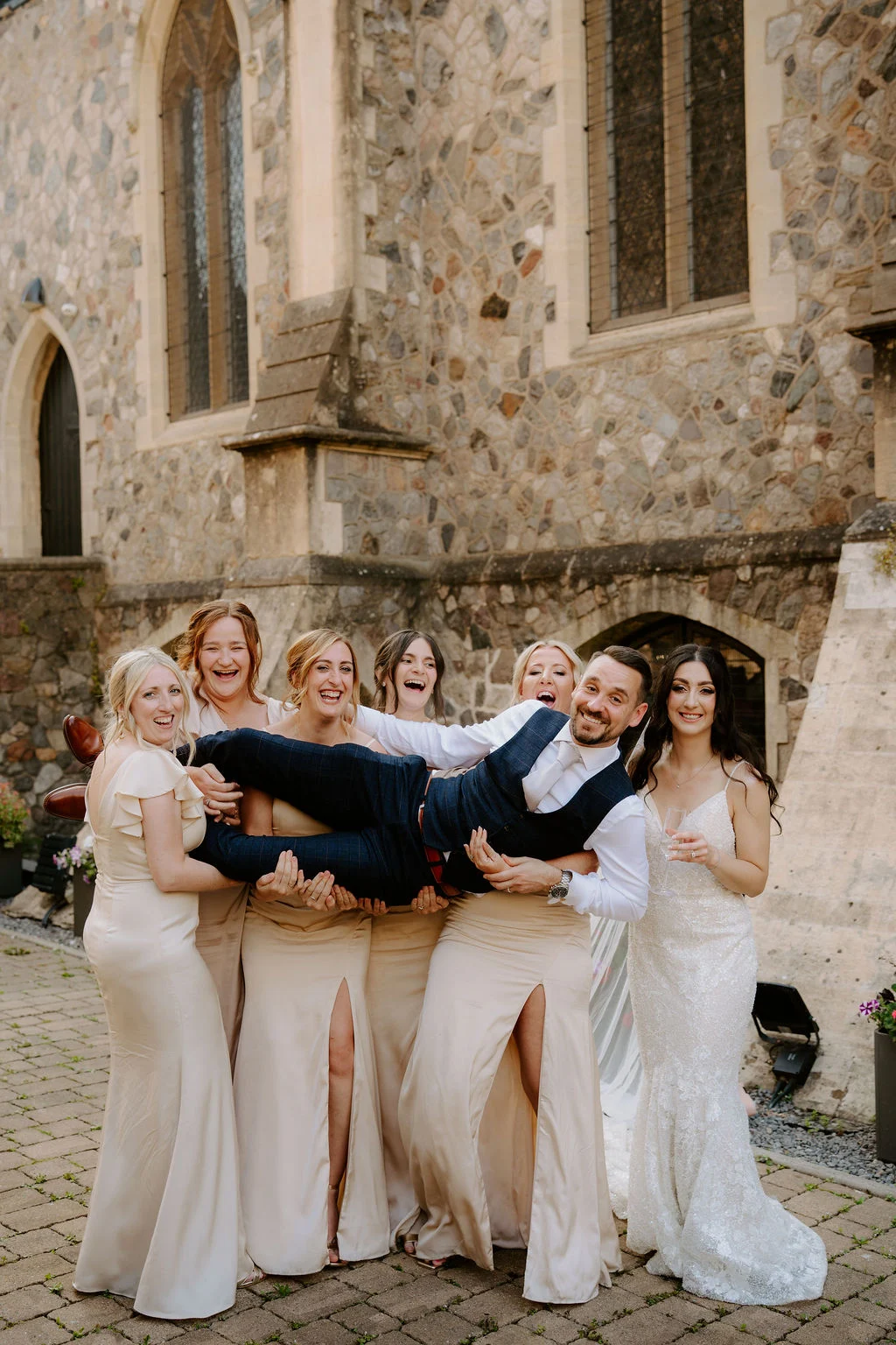 Carla and her bridesmaids holding Callum for a playful group photograph.