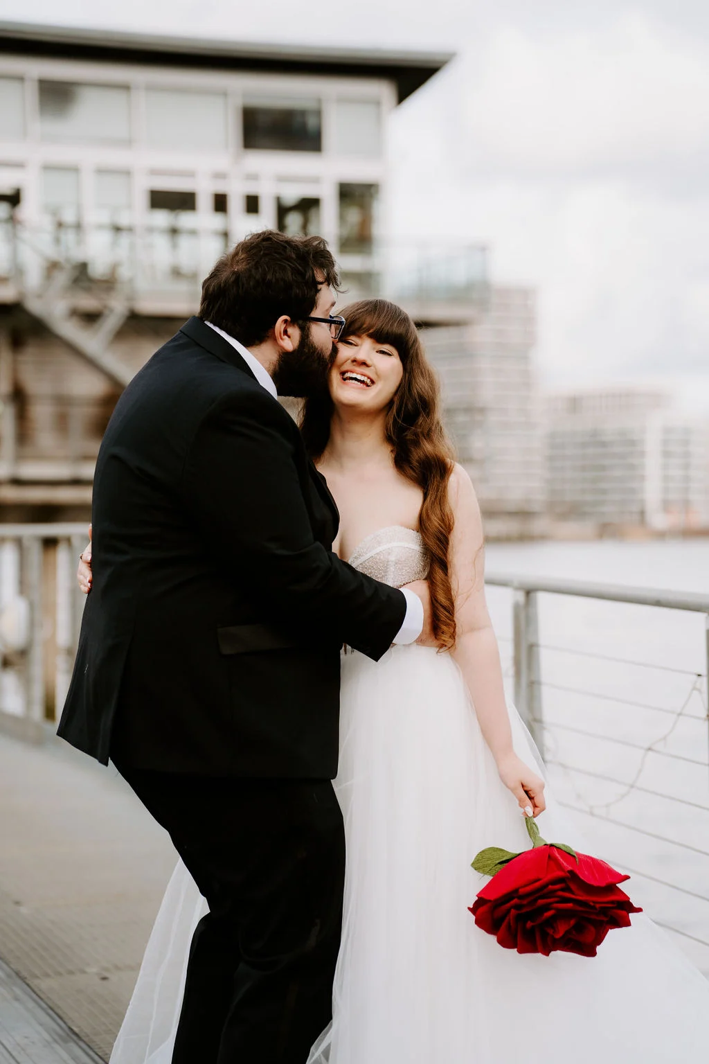 Josie and Nick embracing on the riverside walkway.