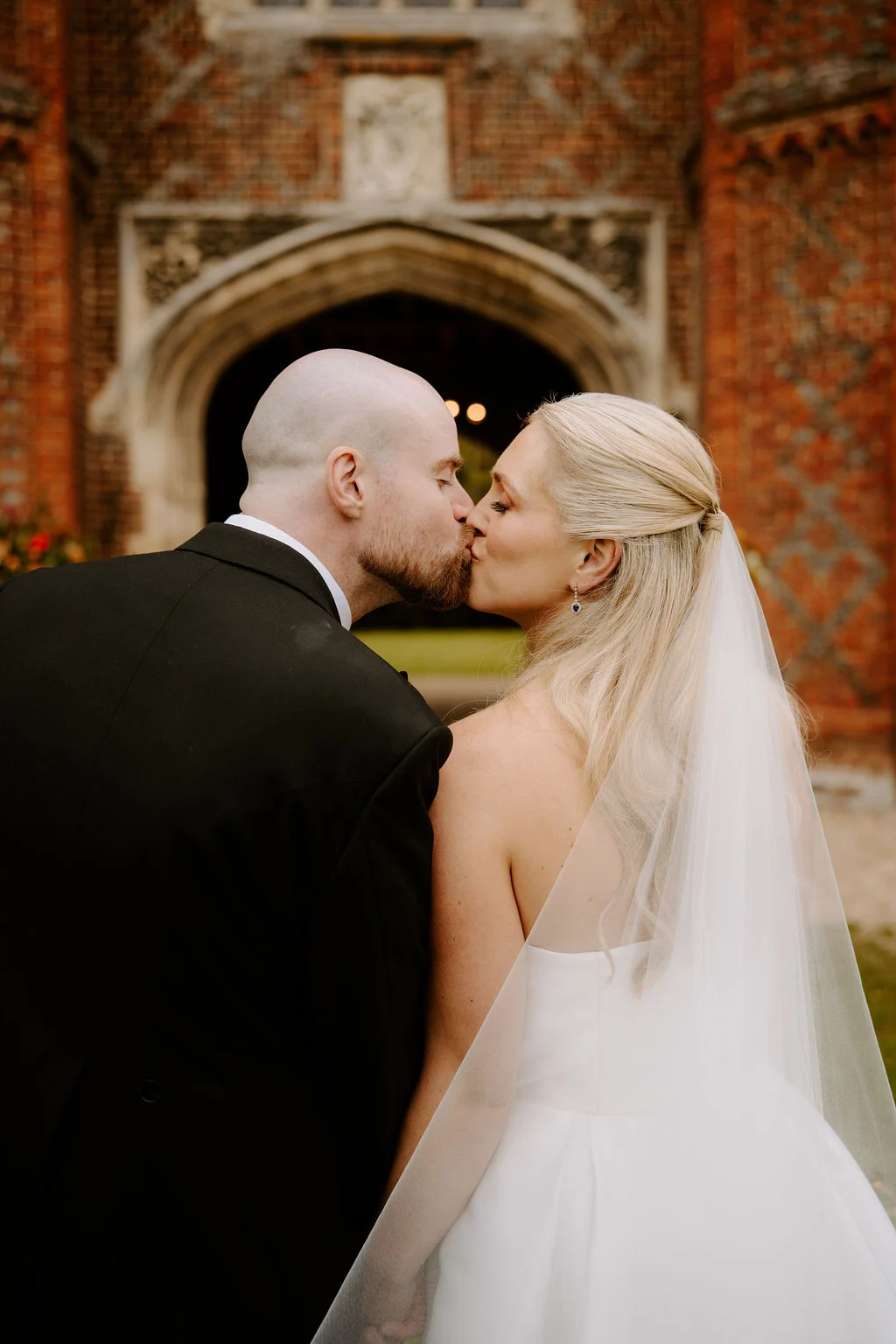 Sophie and Jake kissing beneath a brick arch.