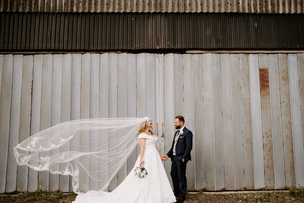 Emma and Sean with her veil catching the breeze outside Beeston Manor