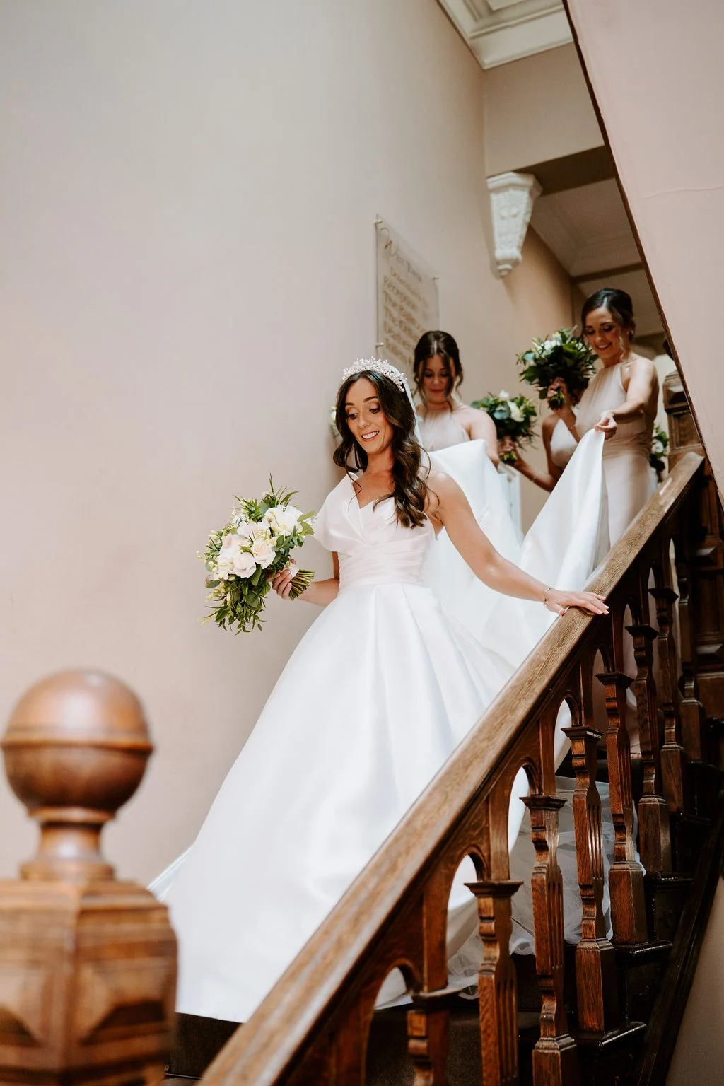 Natalie coming down the staircase with her bridesmaids behind her at West Tower