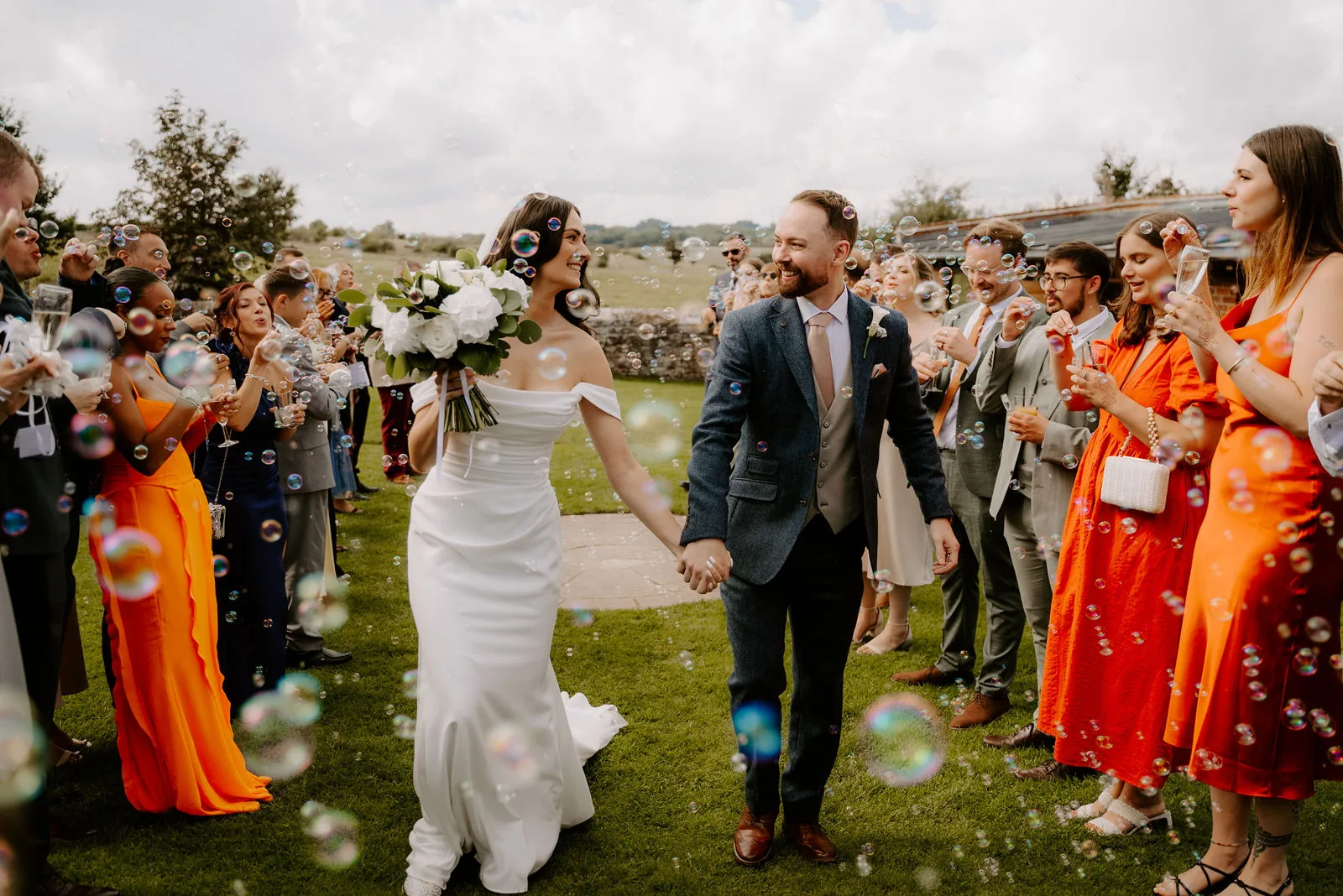 Charlie and Faye laughing together during couple portraits in the surrounding fields at Dodford Manor