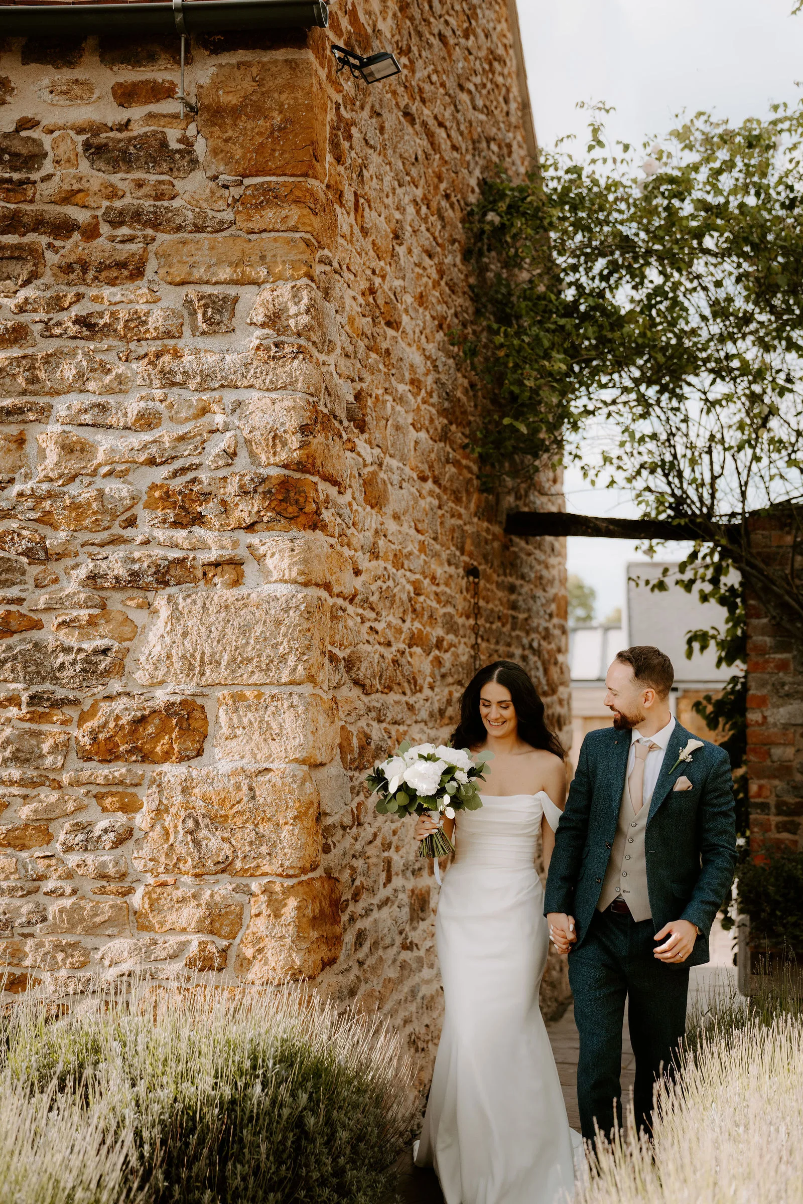 Faye smiling joyfully with her bridal party outside the barns at Dodford Manor
