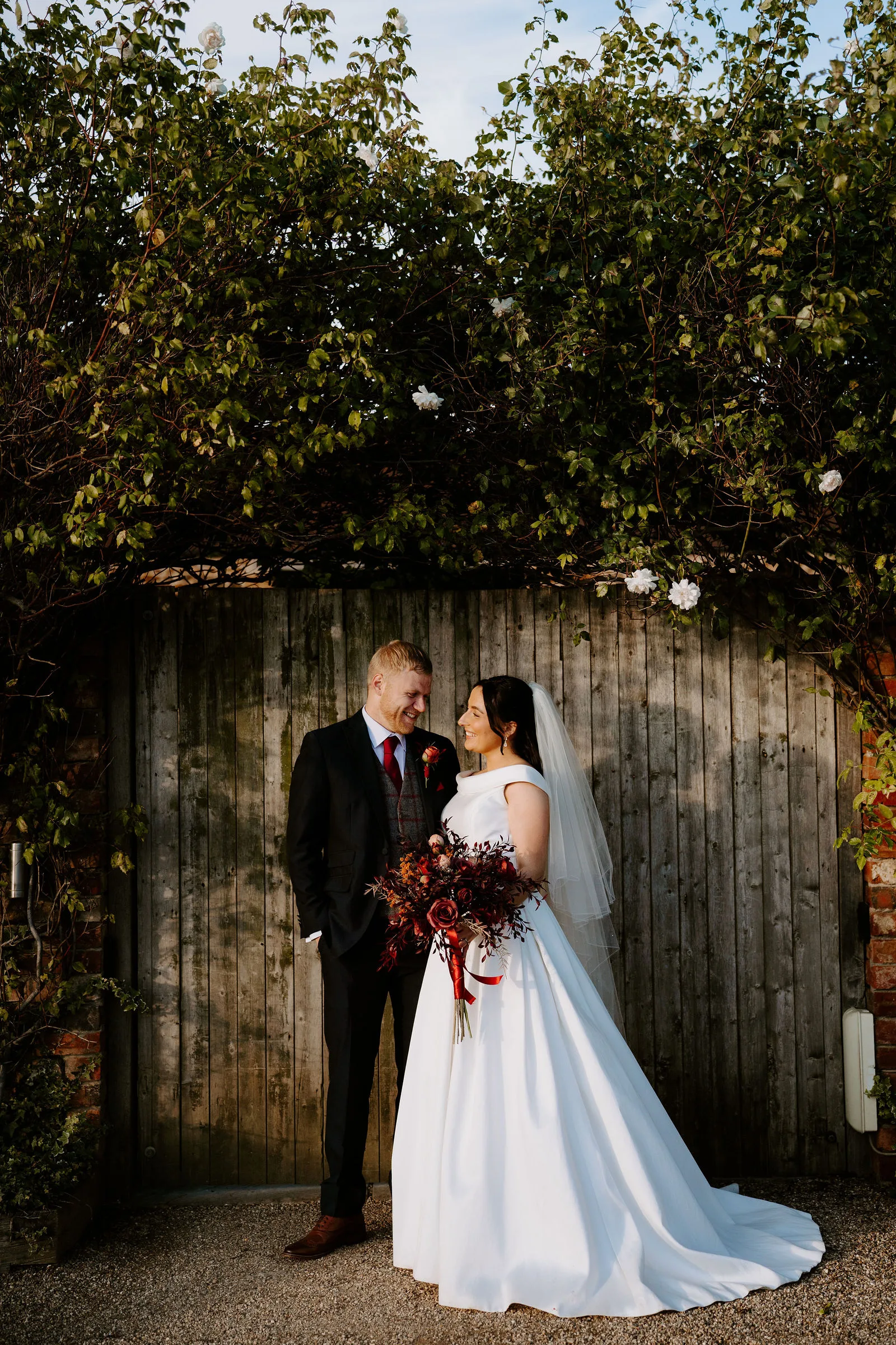Jess and Jack smiling together during autumn couple portraits at Dodford Manor