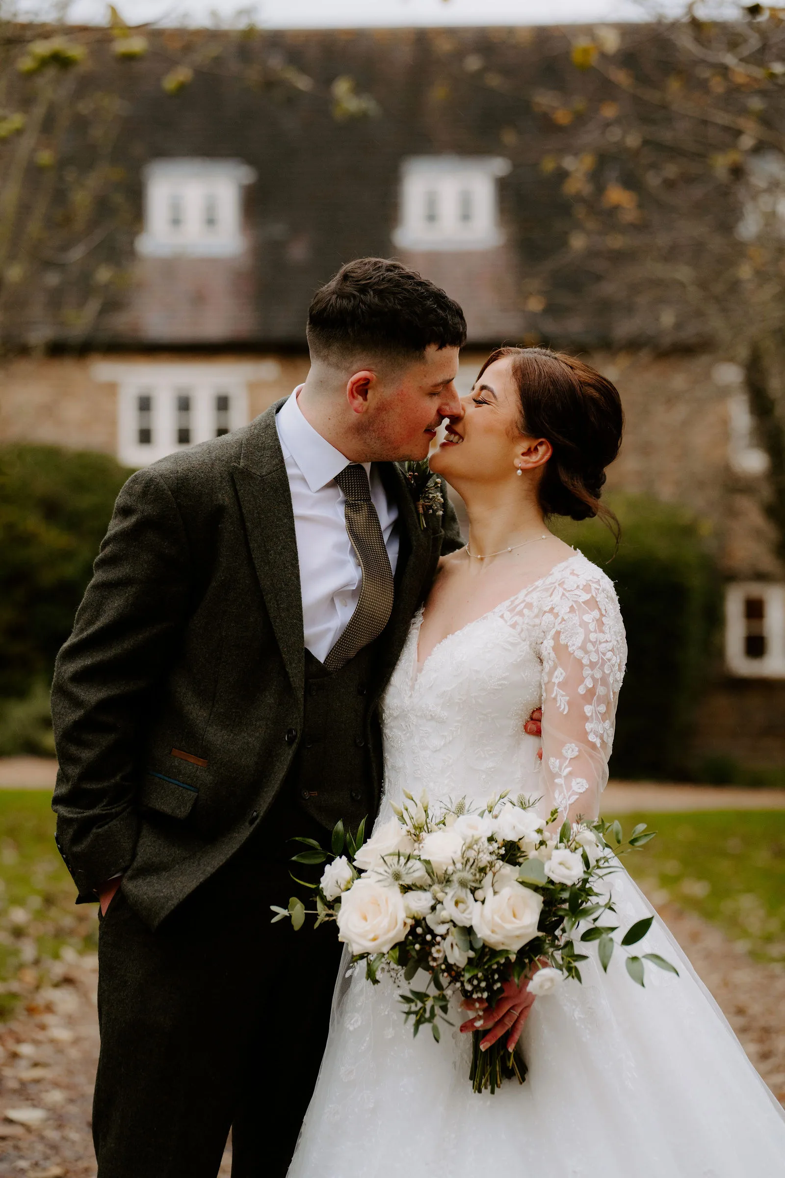 Charlotte and Jack kissing outdoors beside a stone building