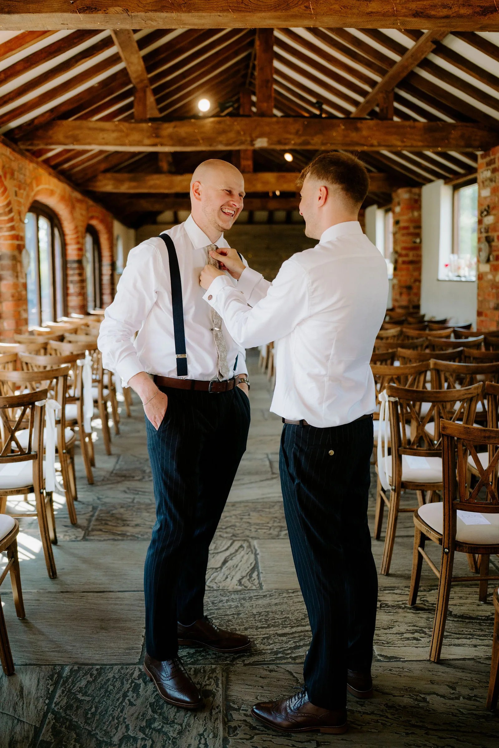 Two guests laughing together beneath the timber beams at Dodmoor House
