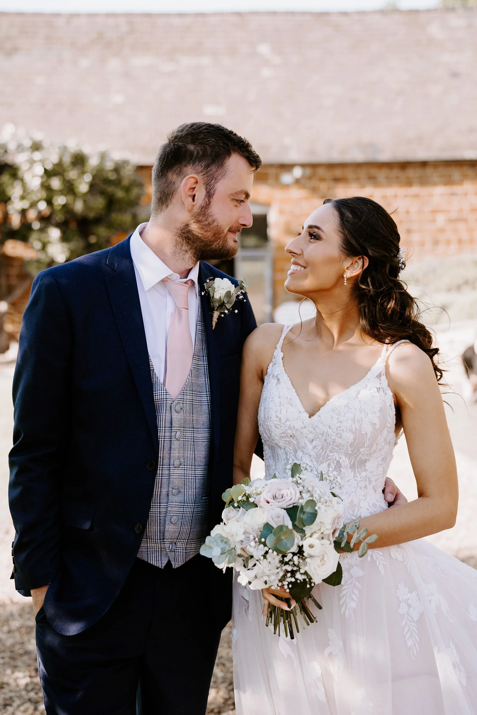 Louise and Brett smiling together in the woodland gardens at The Barns at Hunsbury Hill