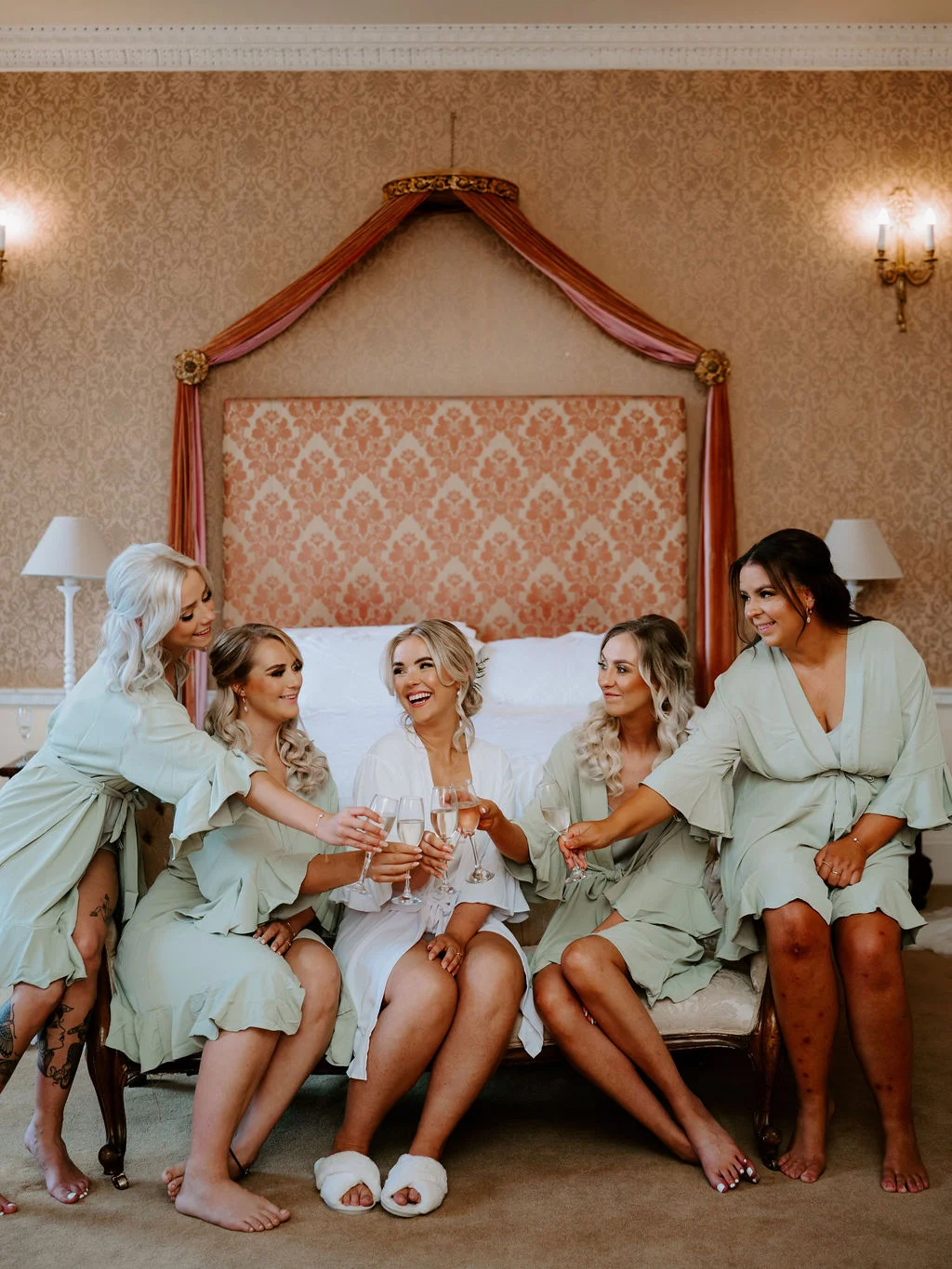 Charlotte and her wedding party laughing together in matching robes at Colwick Hall