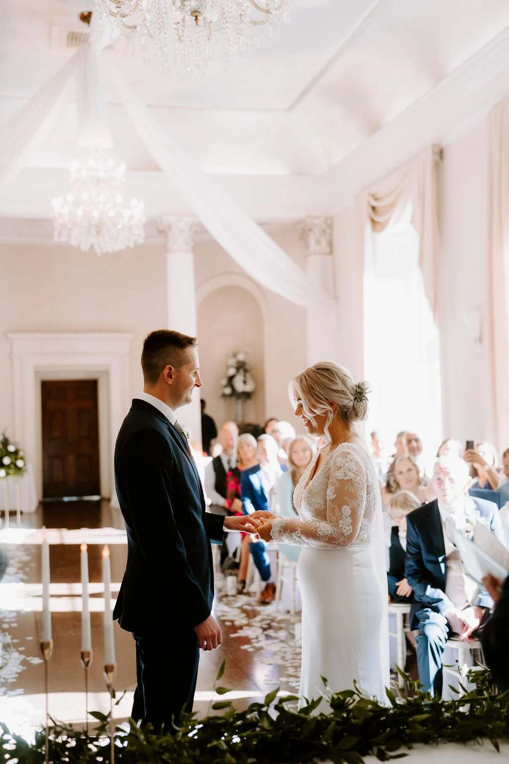 Charlotte and Jake smiling at each other during their indoor wedding ceremony