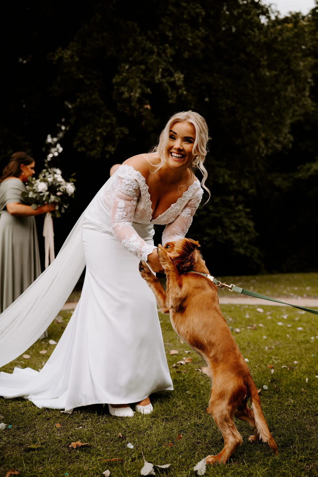Charlotte greeting a dog on the lawn in her wedding dress